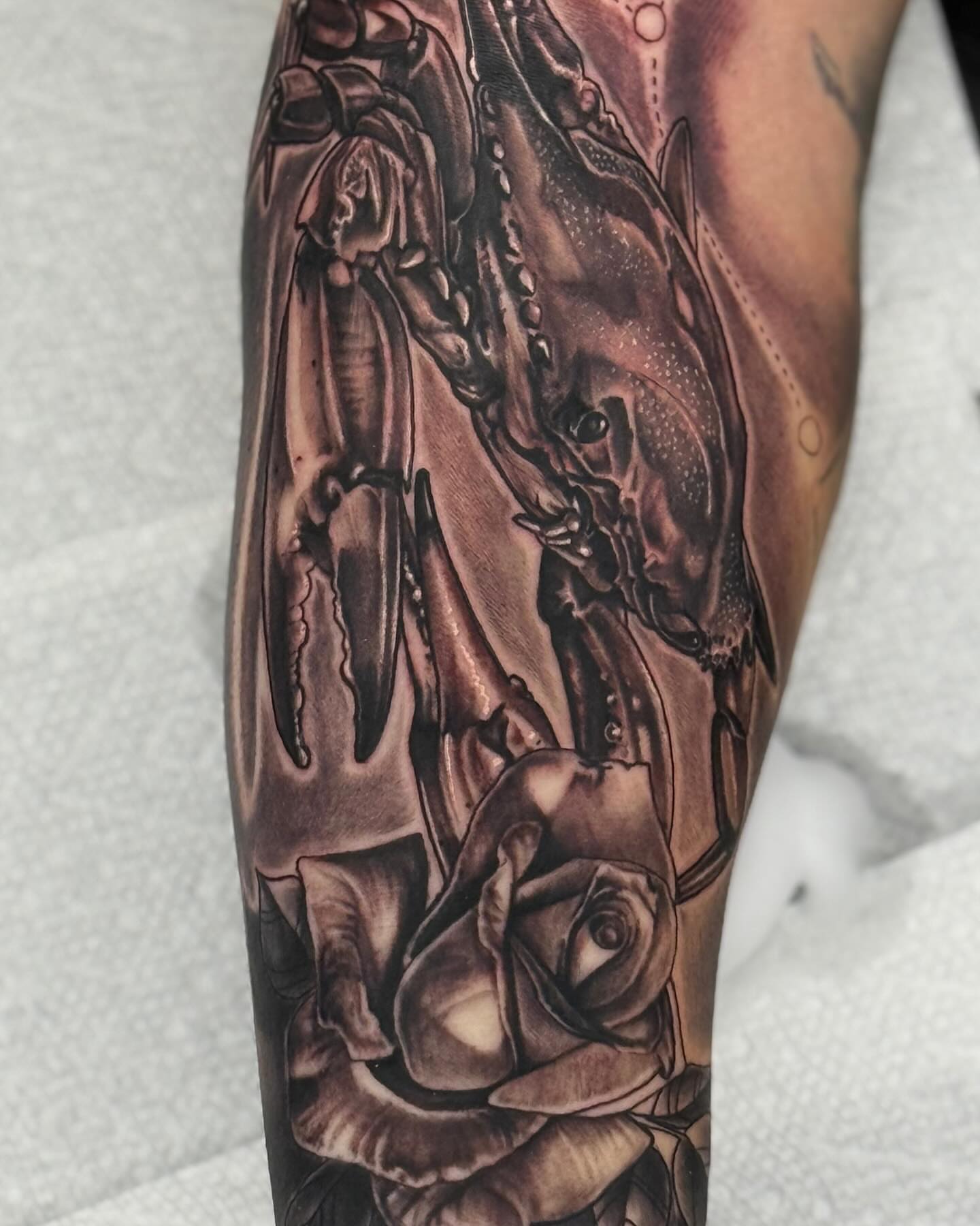 Crab and rose realism tattoo on the forearm by Frank DeMao