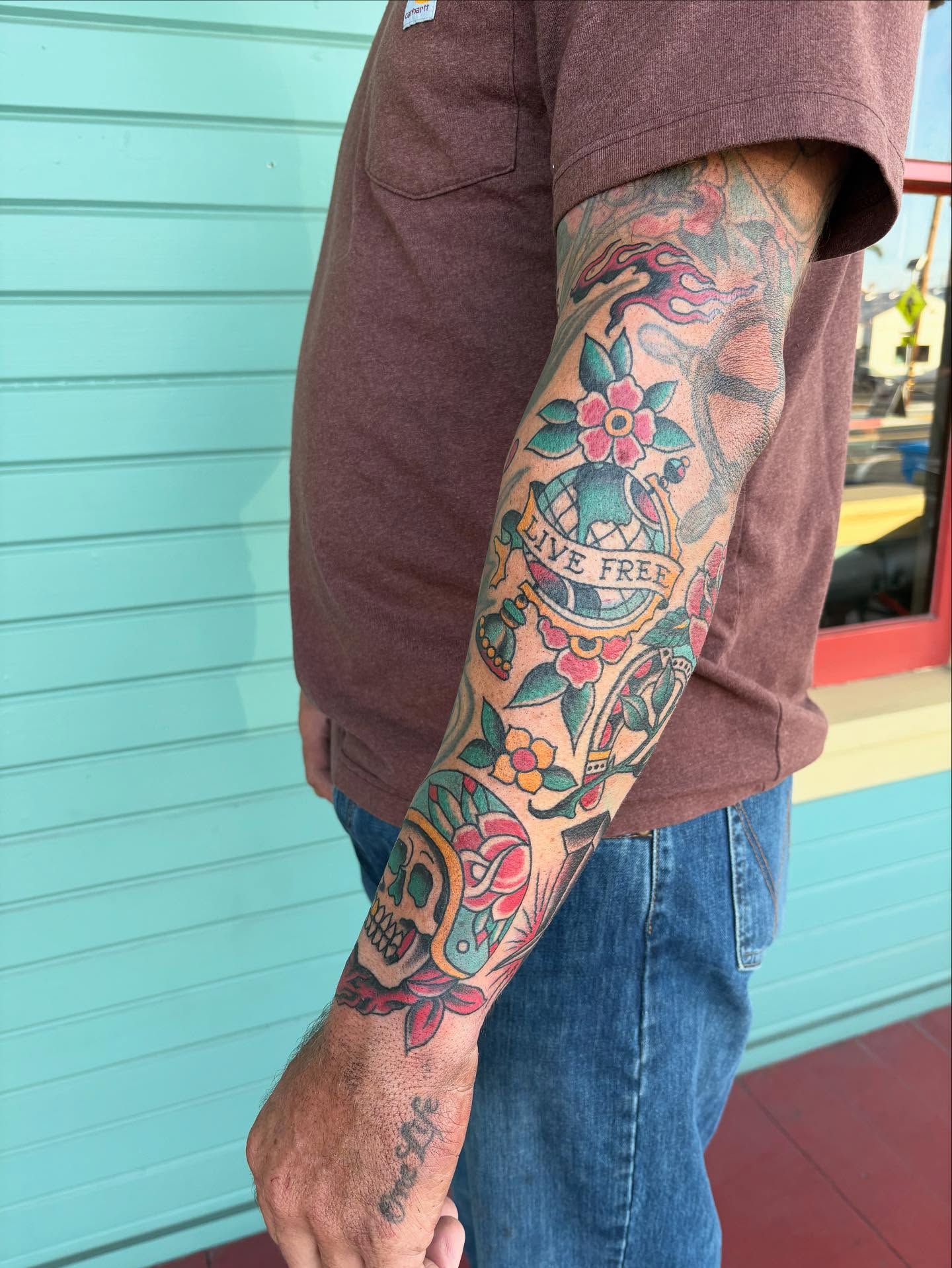 Floral and skull design American traditional tattoo on the forearm by Nick Rodin