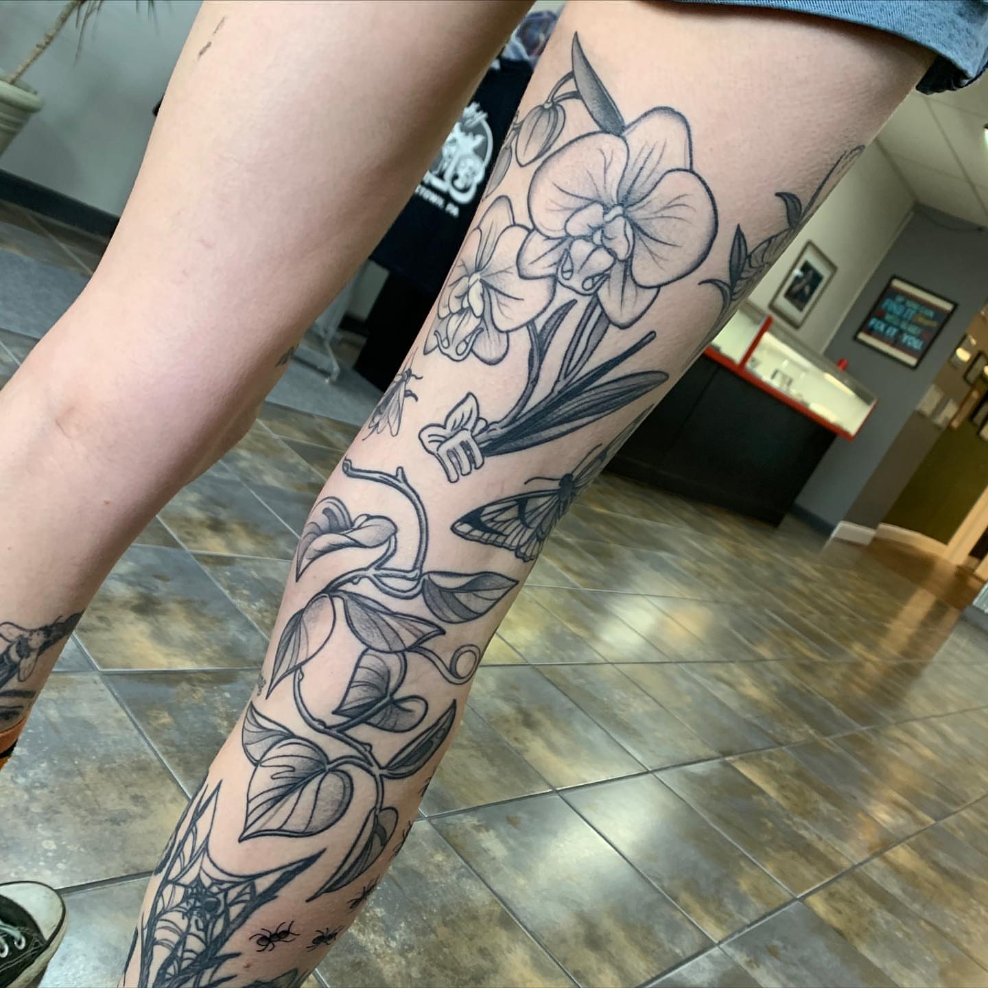 Orchid and moth black and grey tattoo on the forearm by Tabby Wirebach, Kutztown, Pennsylvania