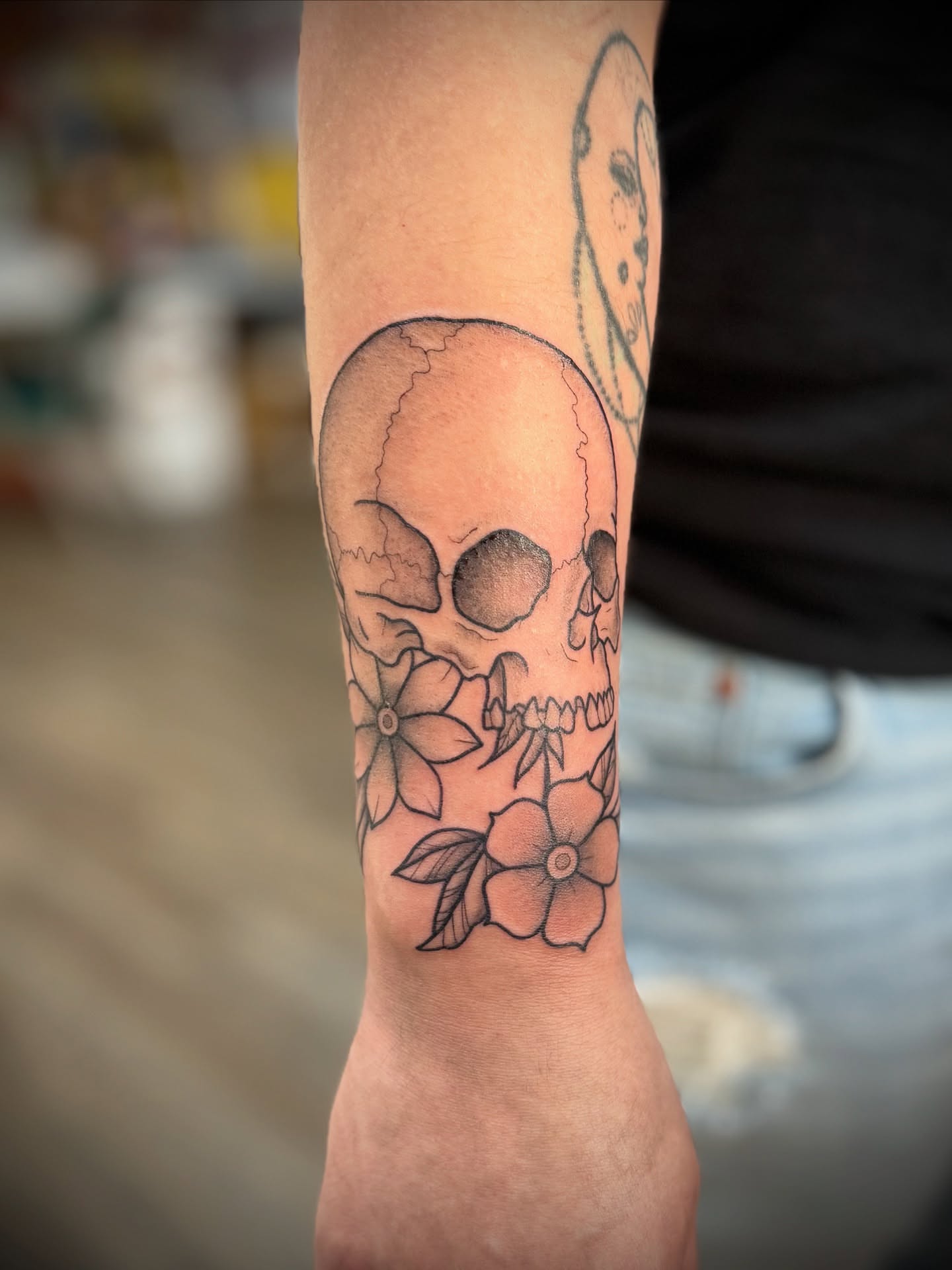 Skull and flowers black and grey tattoo on the forearm by Justin Bianchini - New Orleans Tattoo Artist