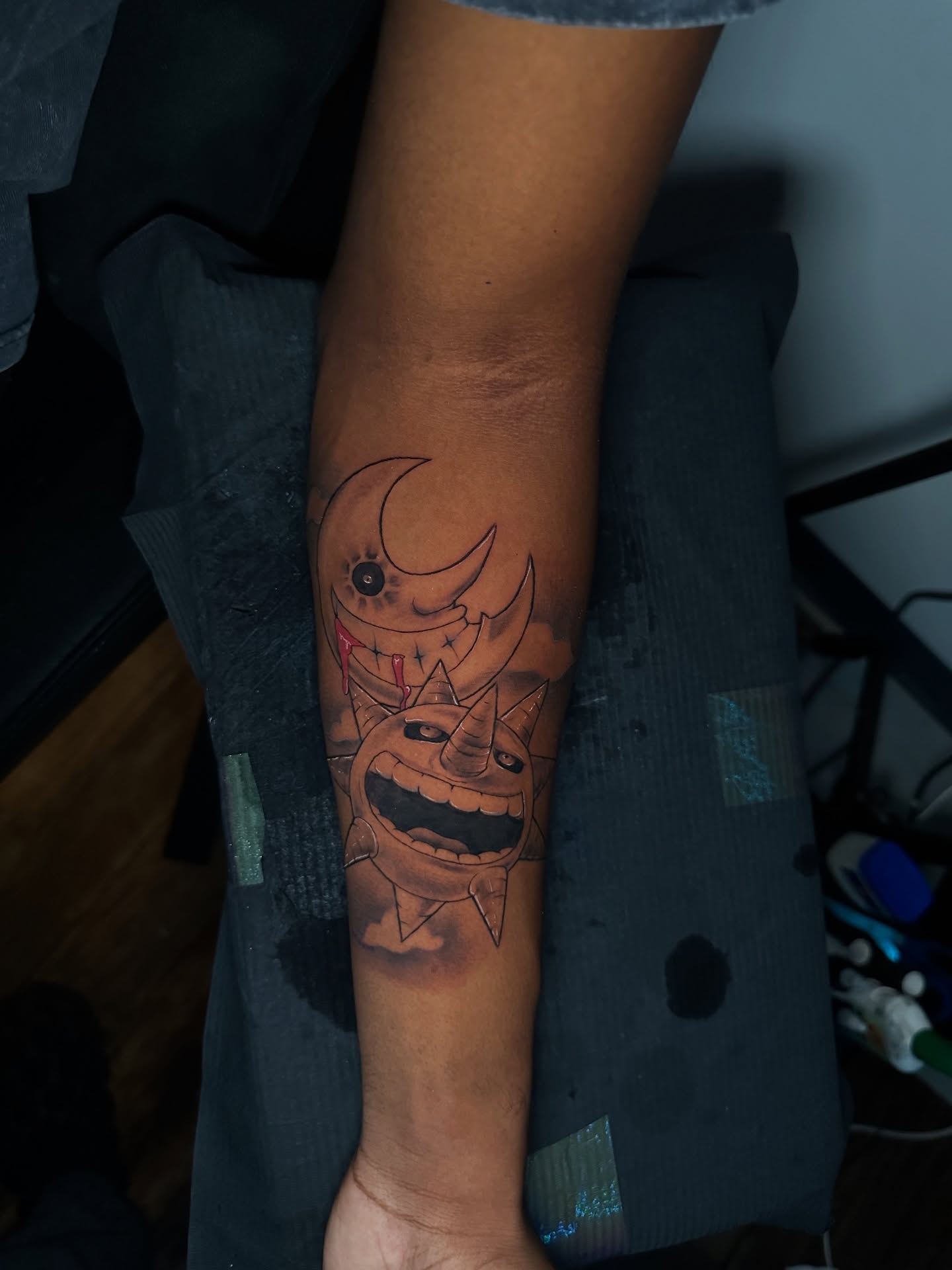 Smiling face with horns black and grey tattoo on the forearm by Chris (Pikasso)