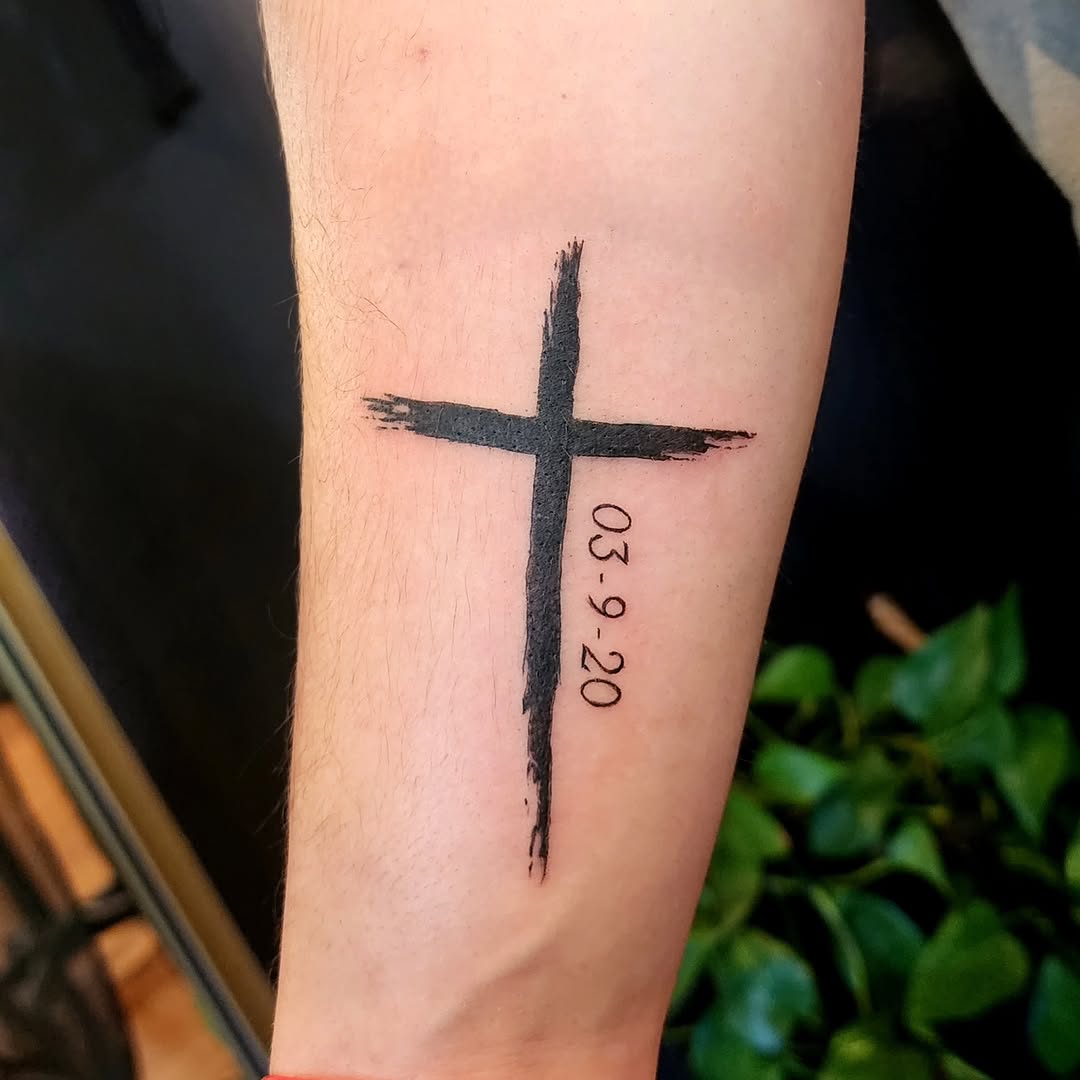 Cross with date fine line tattoo on the forearm by Tim Andrews