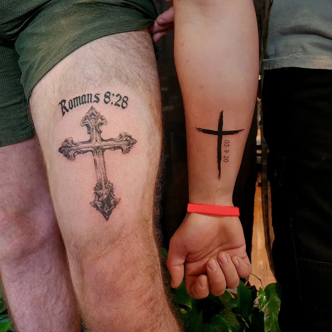Cross with lettering fine line tattoo on the upper arm by Tim Andrews