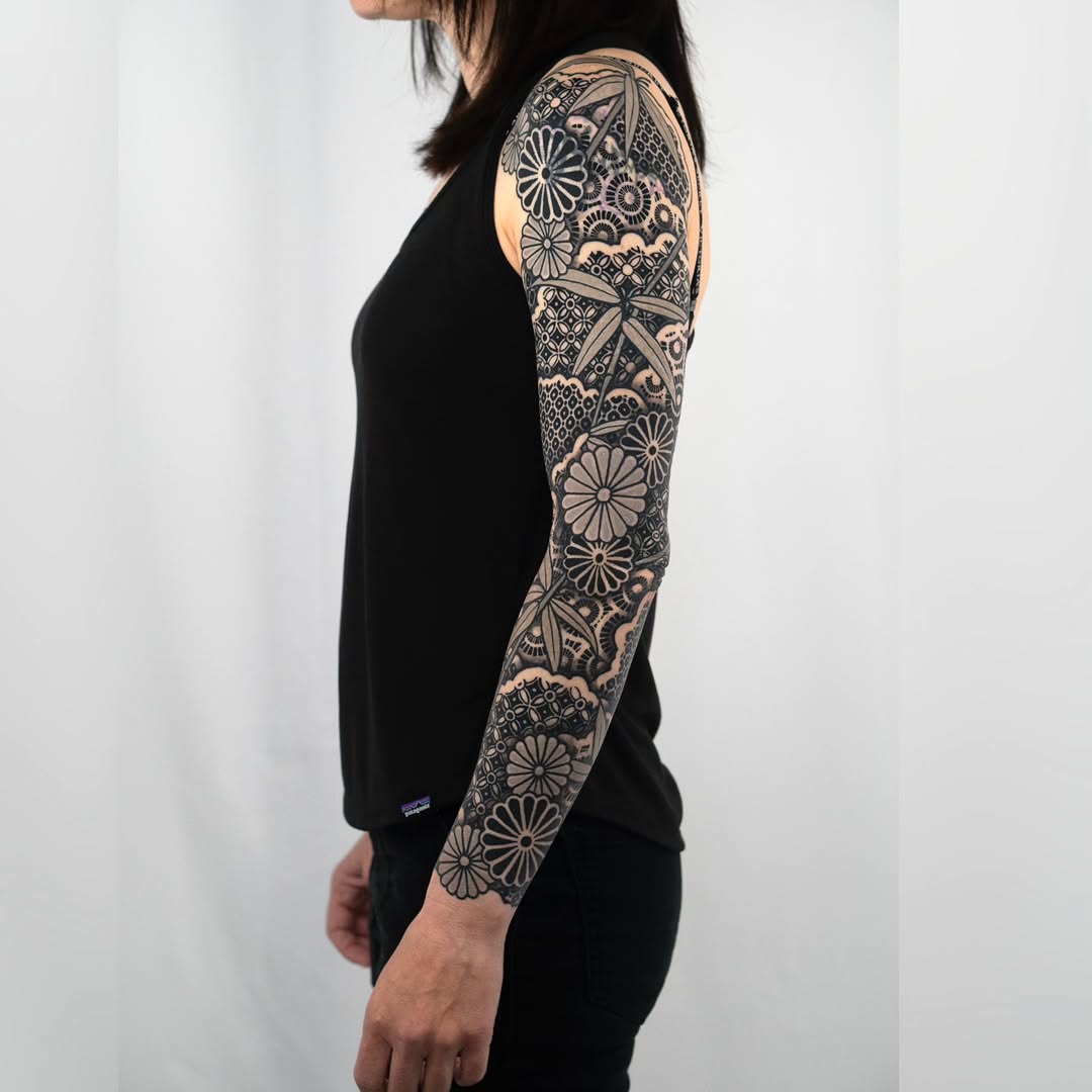 Floral patterns and waves geometric tattoo on the upper arm by Kevin Ligabue