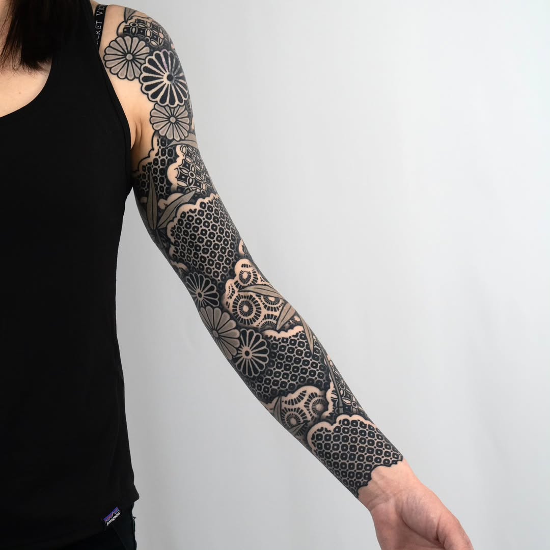 Lace and floral patterns geometric tattoo on the upper arm by Kevin Ligabue