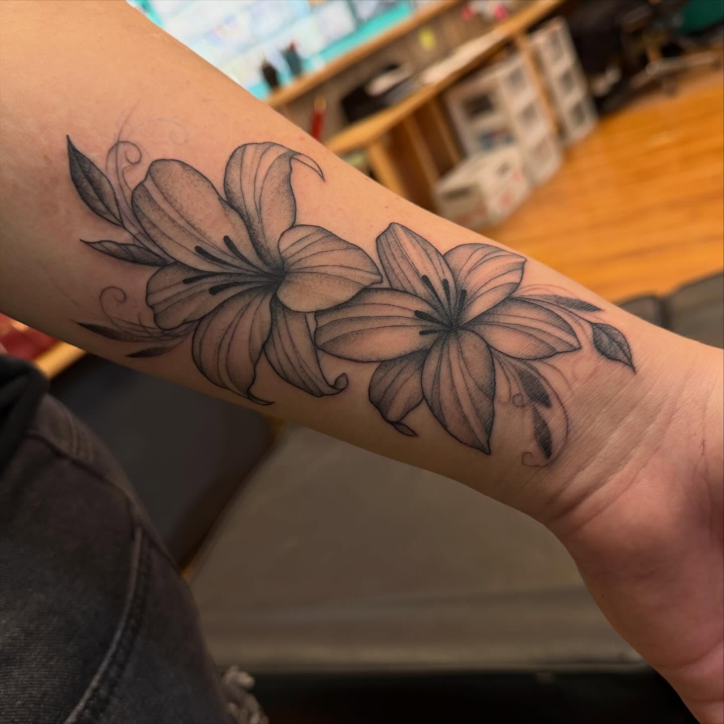 Lilies black and grey tattoo on the forearm by Madilynn Klassen