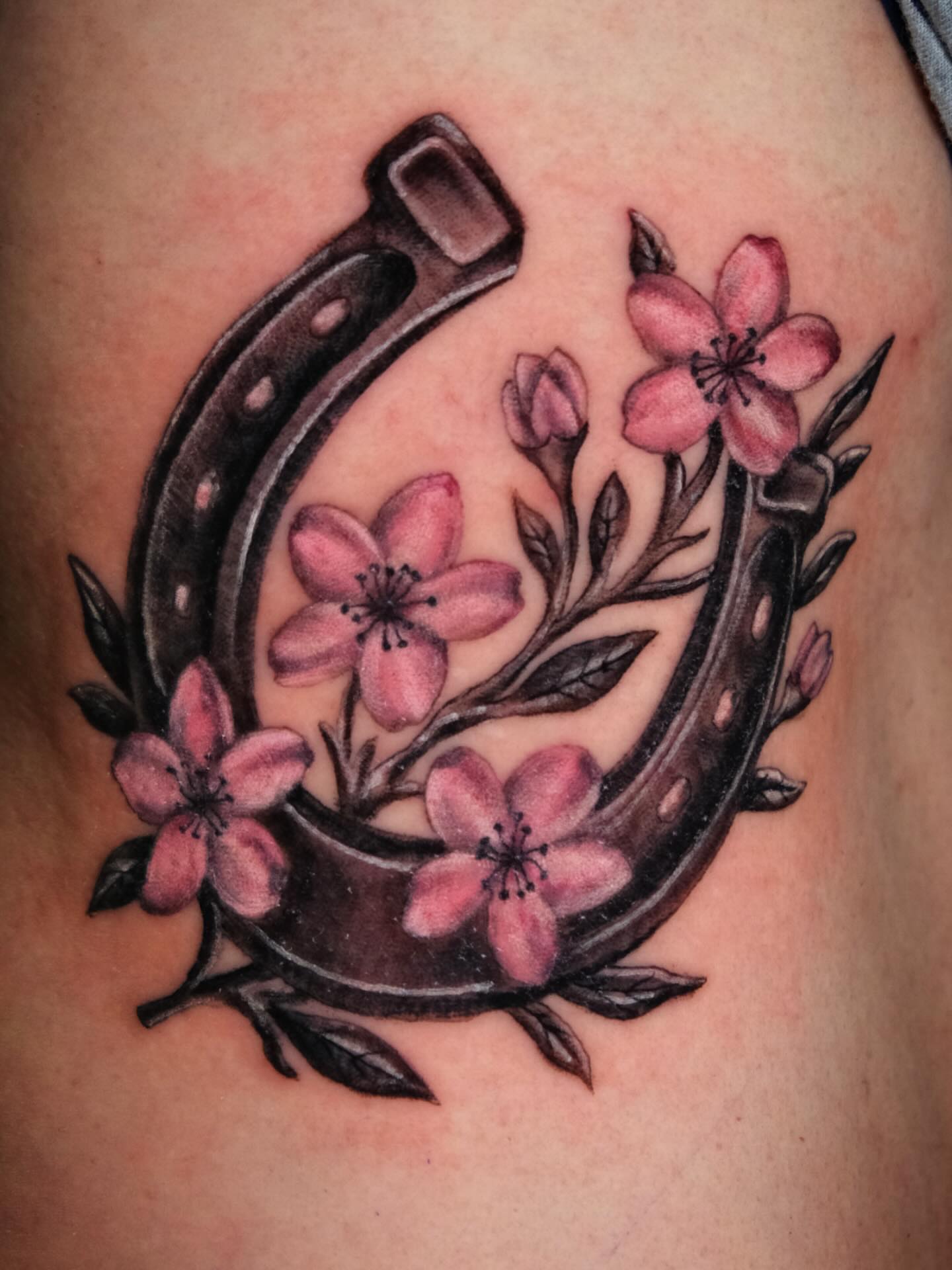 Horseshoe with cherry blossoms American traditional tattoo on the thigh by Suzanne B