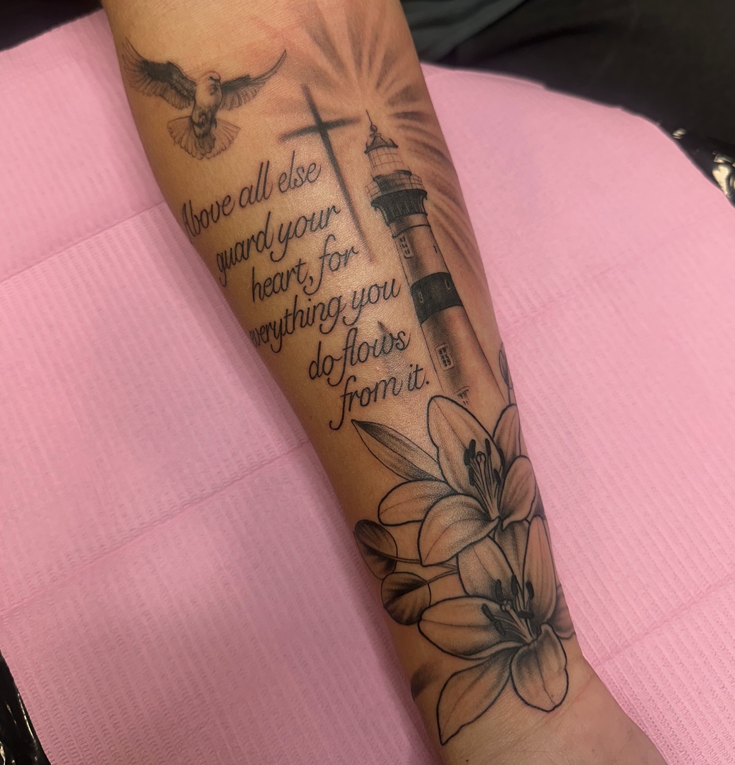 Lighthouse and lilies black and grey tattoo on the forearm by Arielle Deatherage