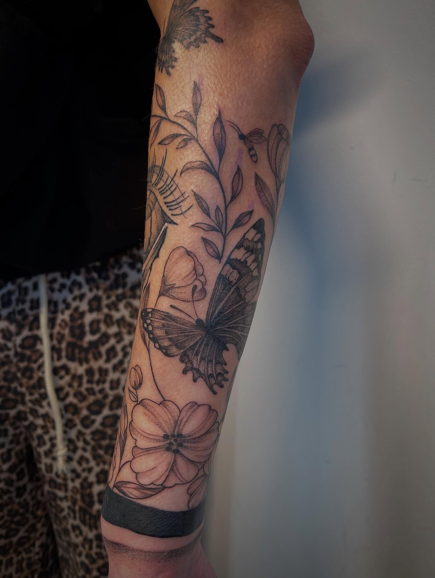 Butterfly and flowers black and grey tattoo on the forearm by Miesha Busker
