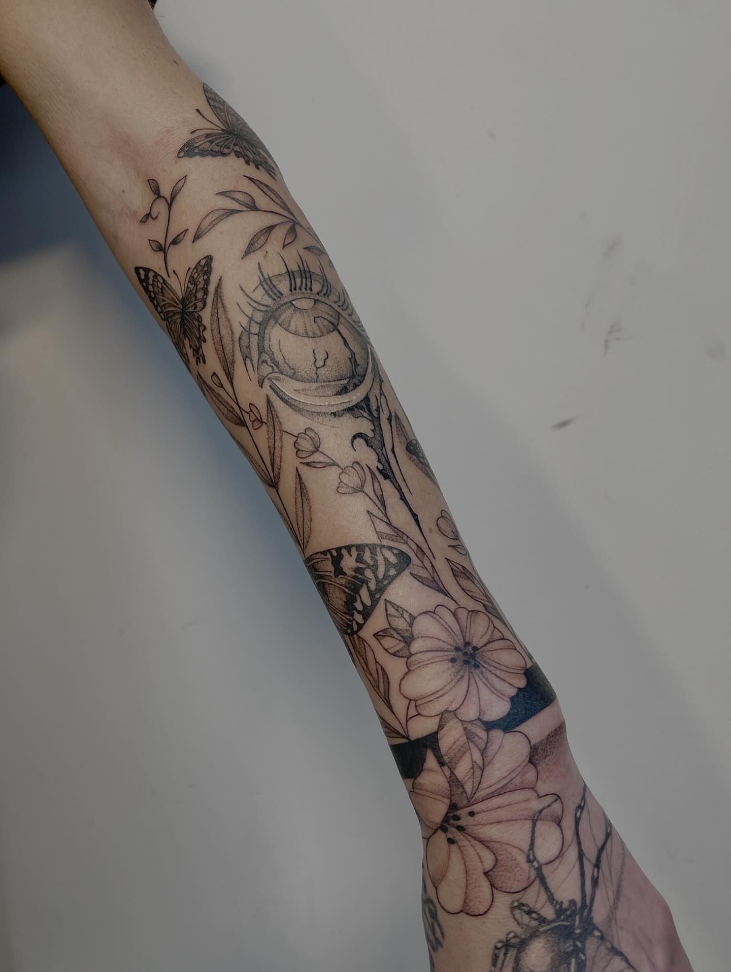 Flowers and butterflies black and grey tattoo on the forearm by Miesha Busker