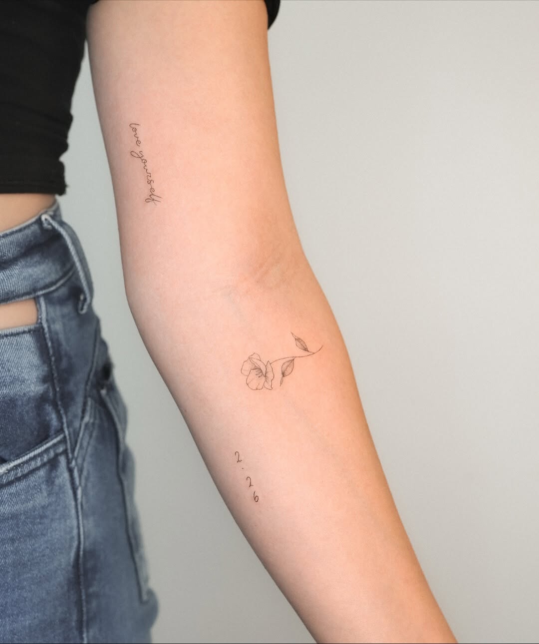 Flower and script minimalist tattoo on the forearm by Fine Line, New York, New York