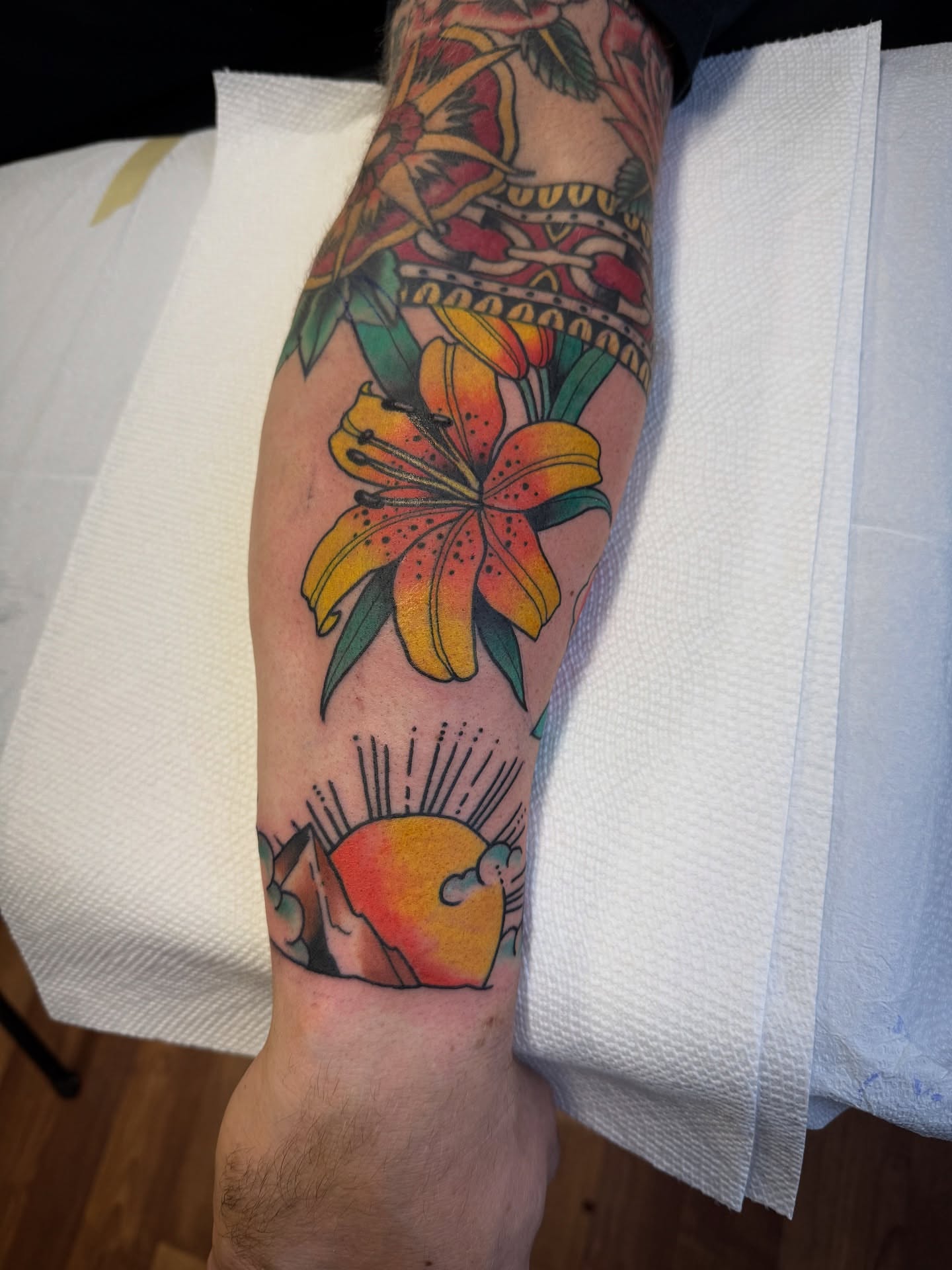 Lily and sun American traditional tattoo on the forearm by Jeremy Utley