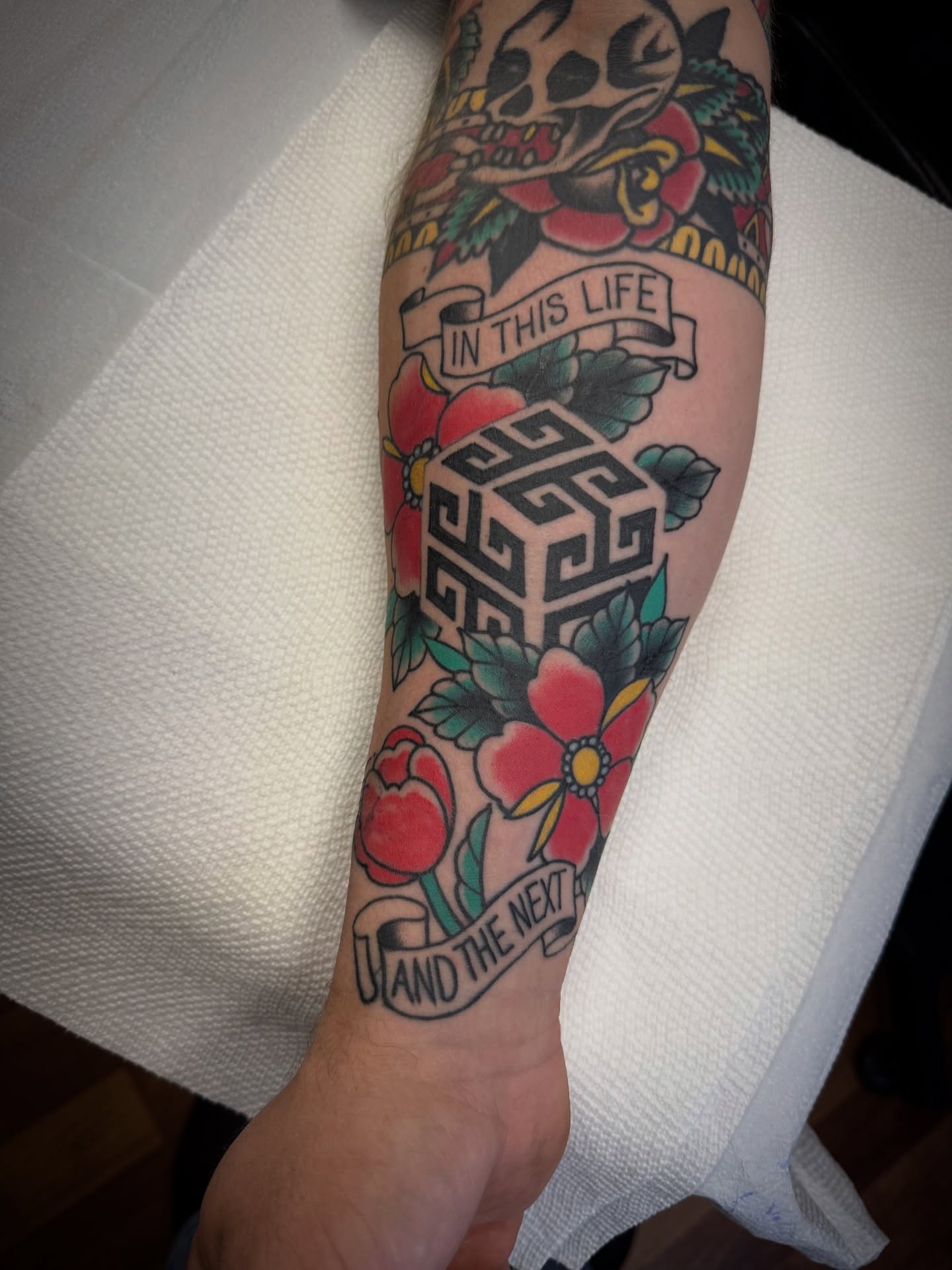 Skull and floral American traditional tattoo on the forearm by Jeremy Utley