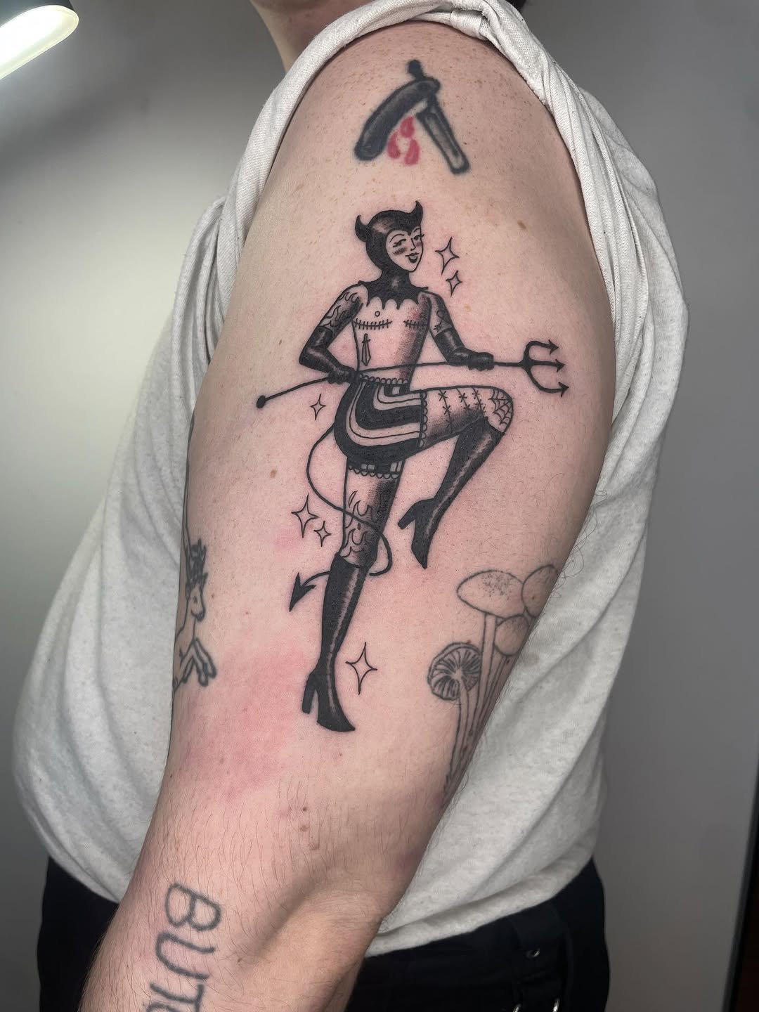 Devil girl with trident neo-traditional tattoo on the upper arm by Fin :