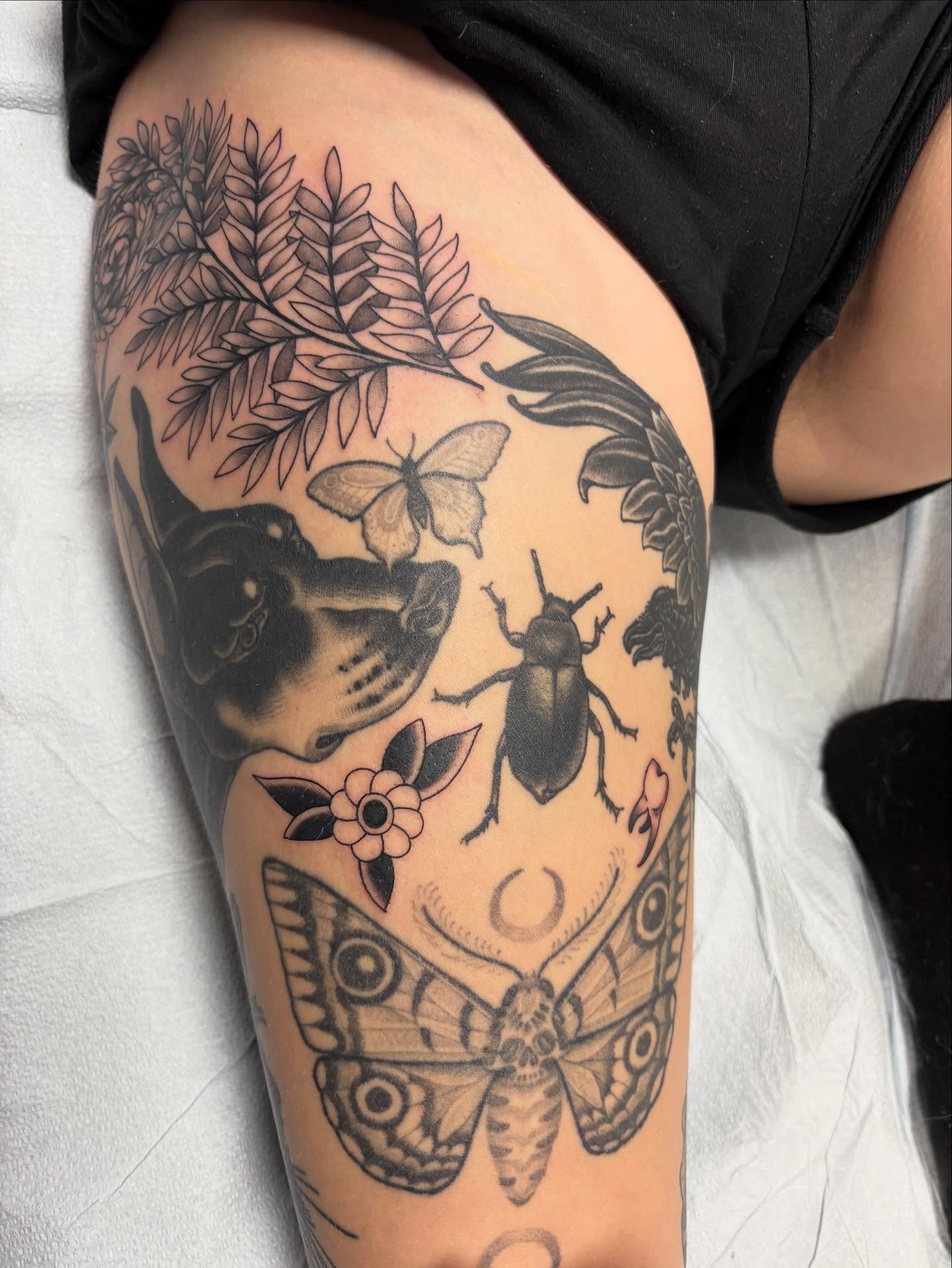 Insects and flowers black and grey tattoo on the thigh by Jakob Ristau, Kansas City, Missouri