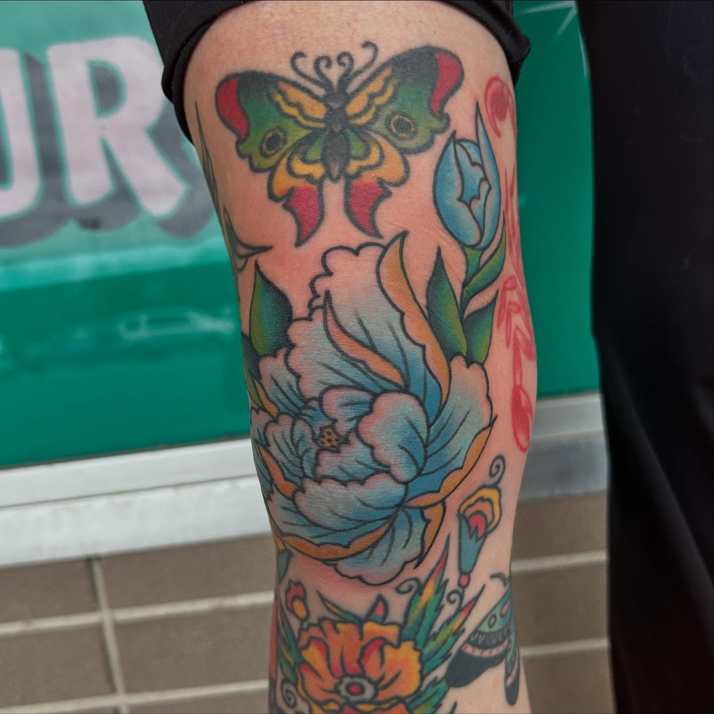 Butterfly and floral American traditional tattoo on the forearm by Atom Aker
