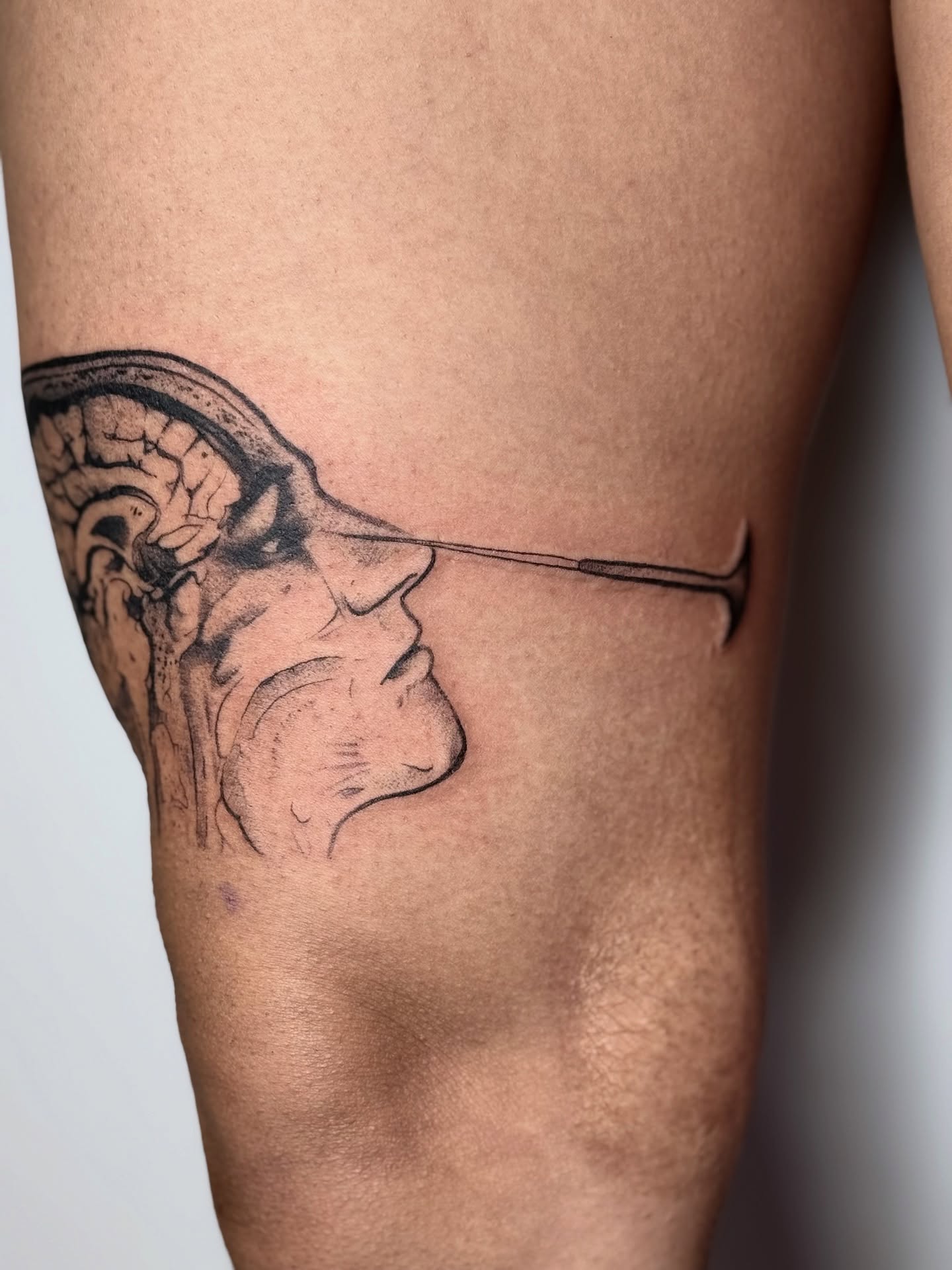 Man's face black and grey tattoo on the thigh by Abrianna