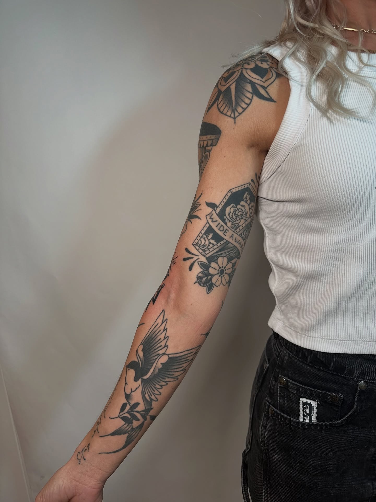 Bird and floral American traditional tattoo on the forearm by Heather Cherish