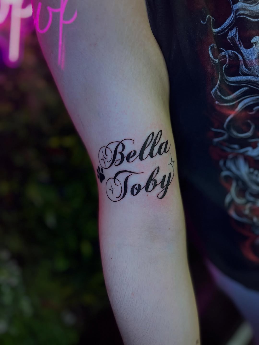 Bella Toby names with paw print lettering tattoo on the forearm by ๐๐ข๐ฃ๐ฑ ๐๐ฆ๐ฑ๐ฌ ๐๏ธ