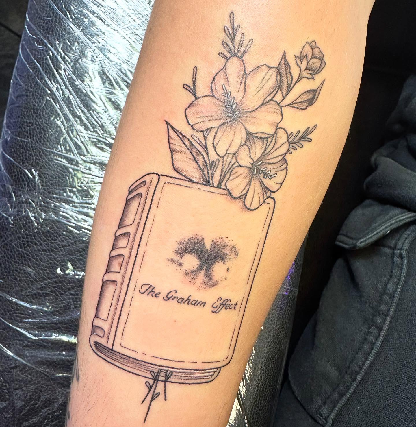 Book with flowers realism tattoo on the forearm by Sarah Nash