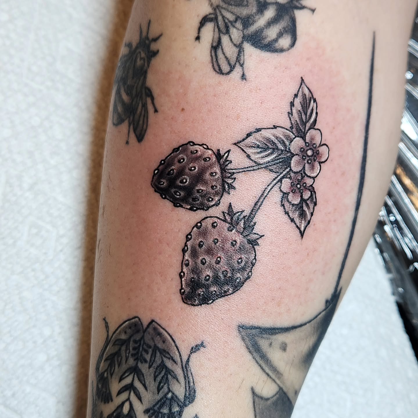 Strawberries and flowers black and grey tattoo on the forearm by Heather