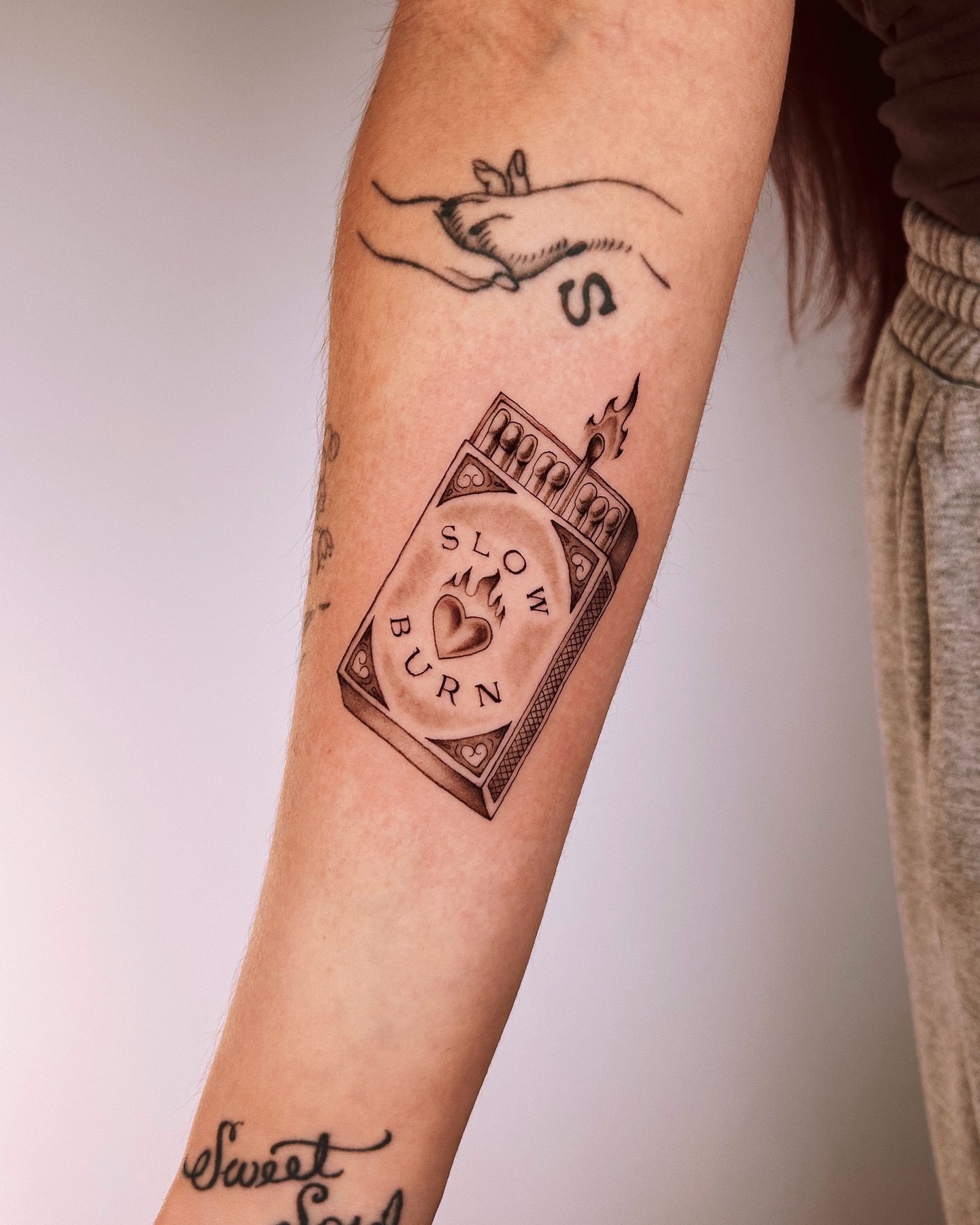 Matches and heart black and grey tattoo on the forearm by Montana Chambers