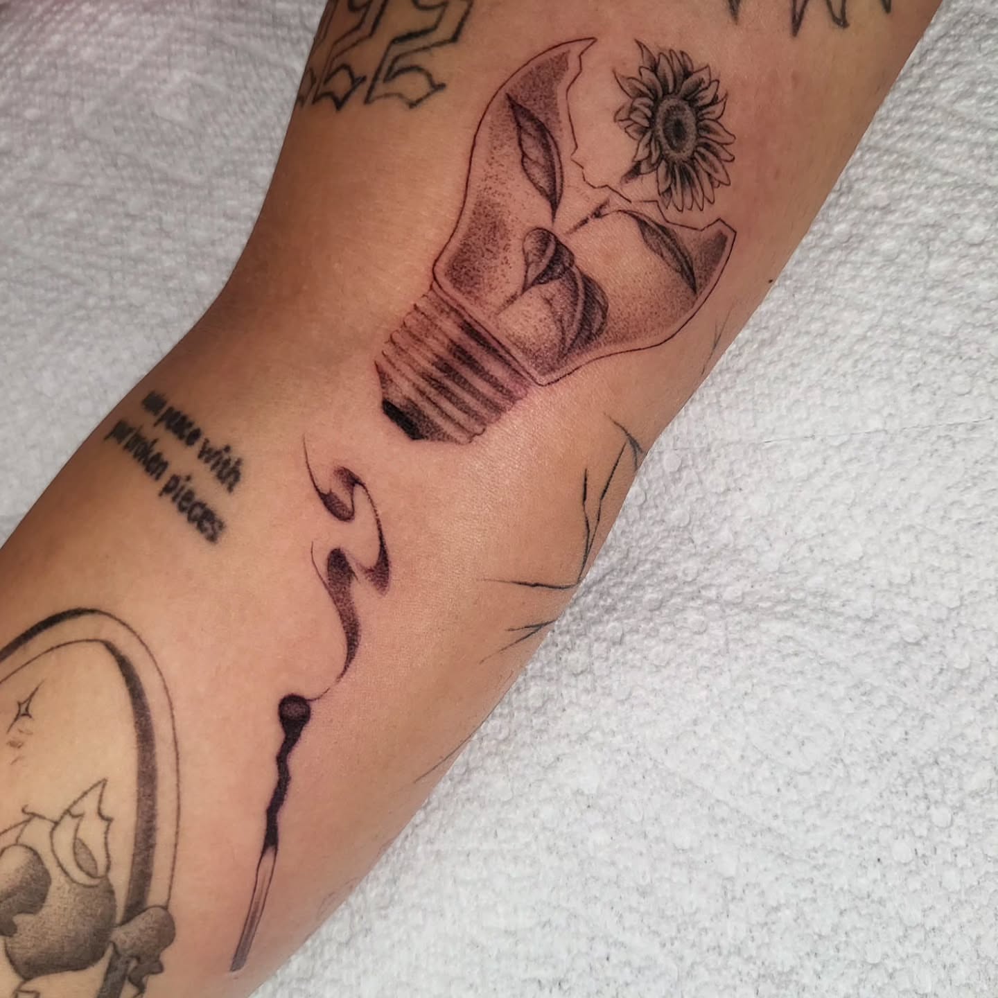 Broken light bulb with sunflower realism tattoo on the forearm by Brenda Juarez - Tattoo Artist