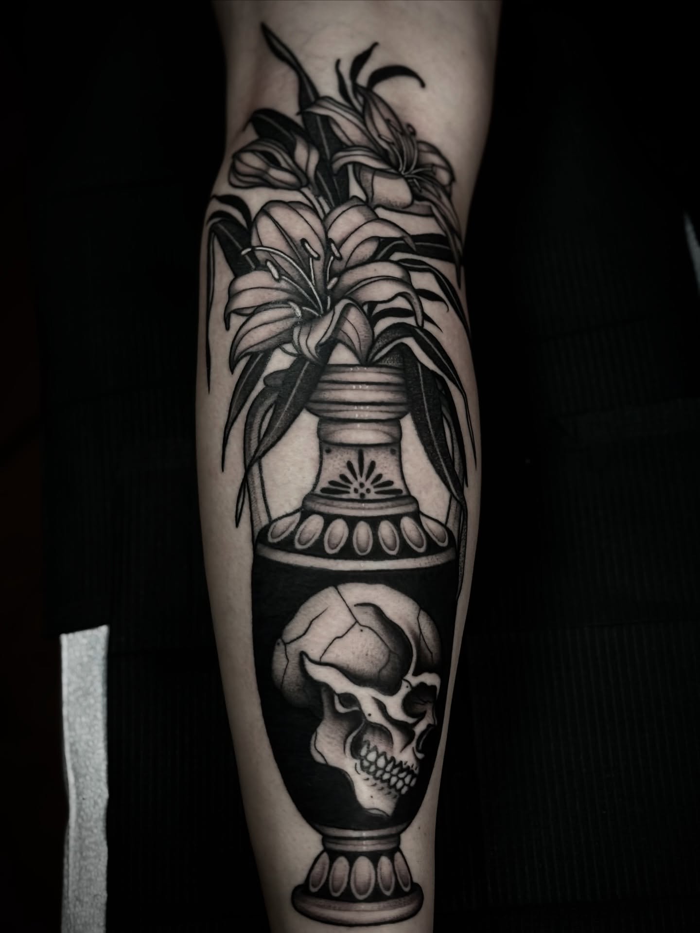 Lilies and skull realism tattoo on the forearm by Ally noel