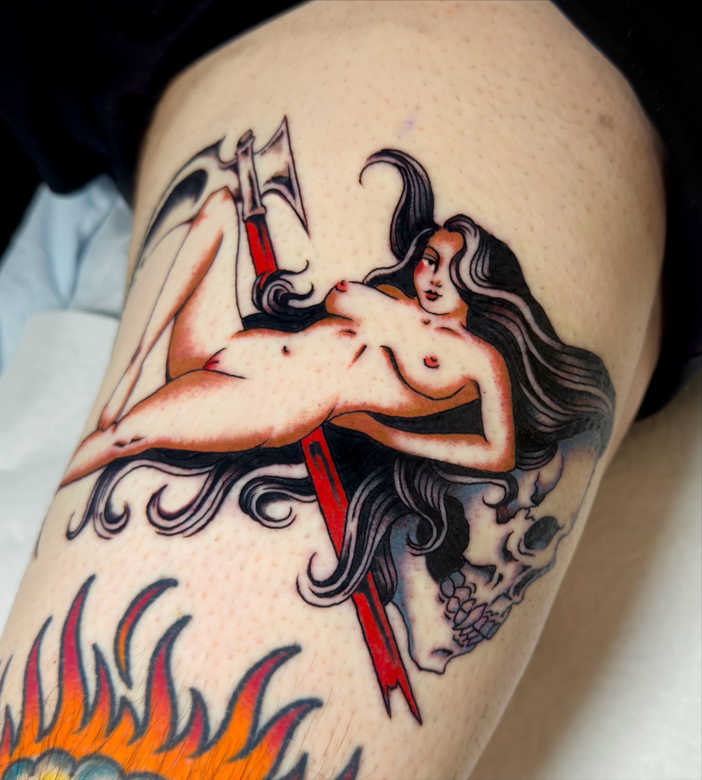 Nude woman with axe American traditional tattoo on the thigh by Haley Tucker, Sebastopol, California