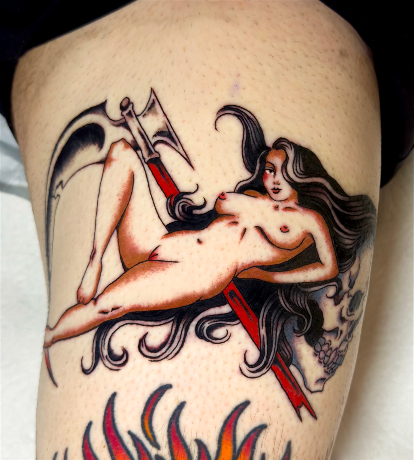 Naked woman with scythe American traditional tattoo on the thigh by Haley Tucker, Sebastopol, California