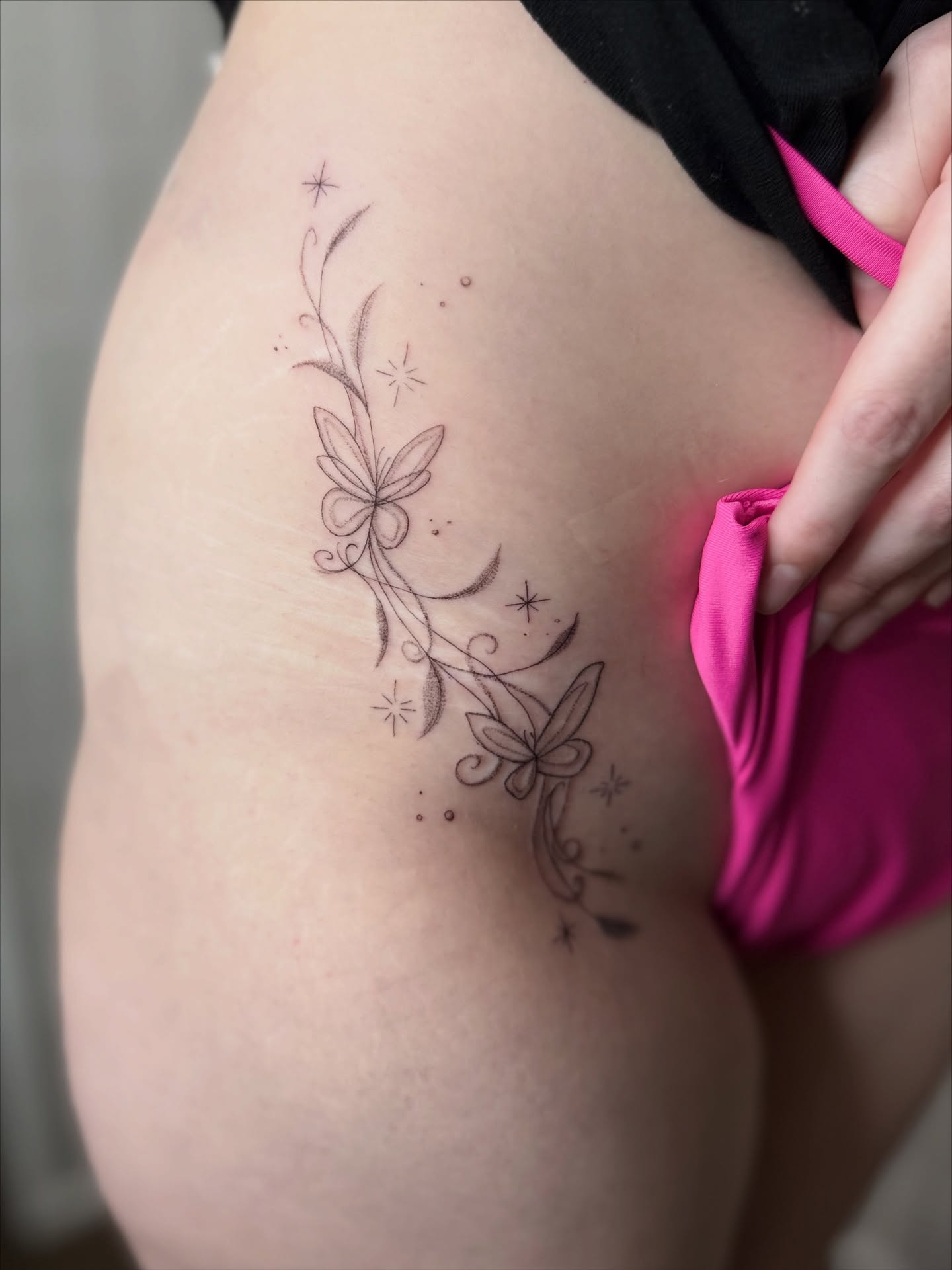 Butterfly and floral fine line tattoo on the thigh by Dama