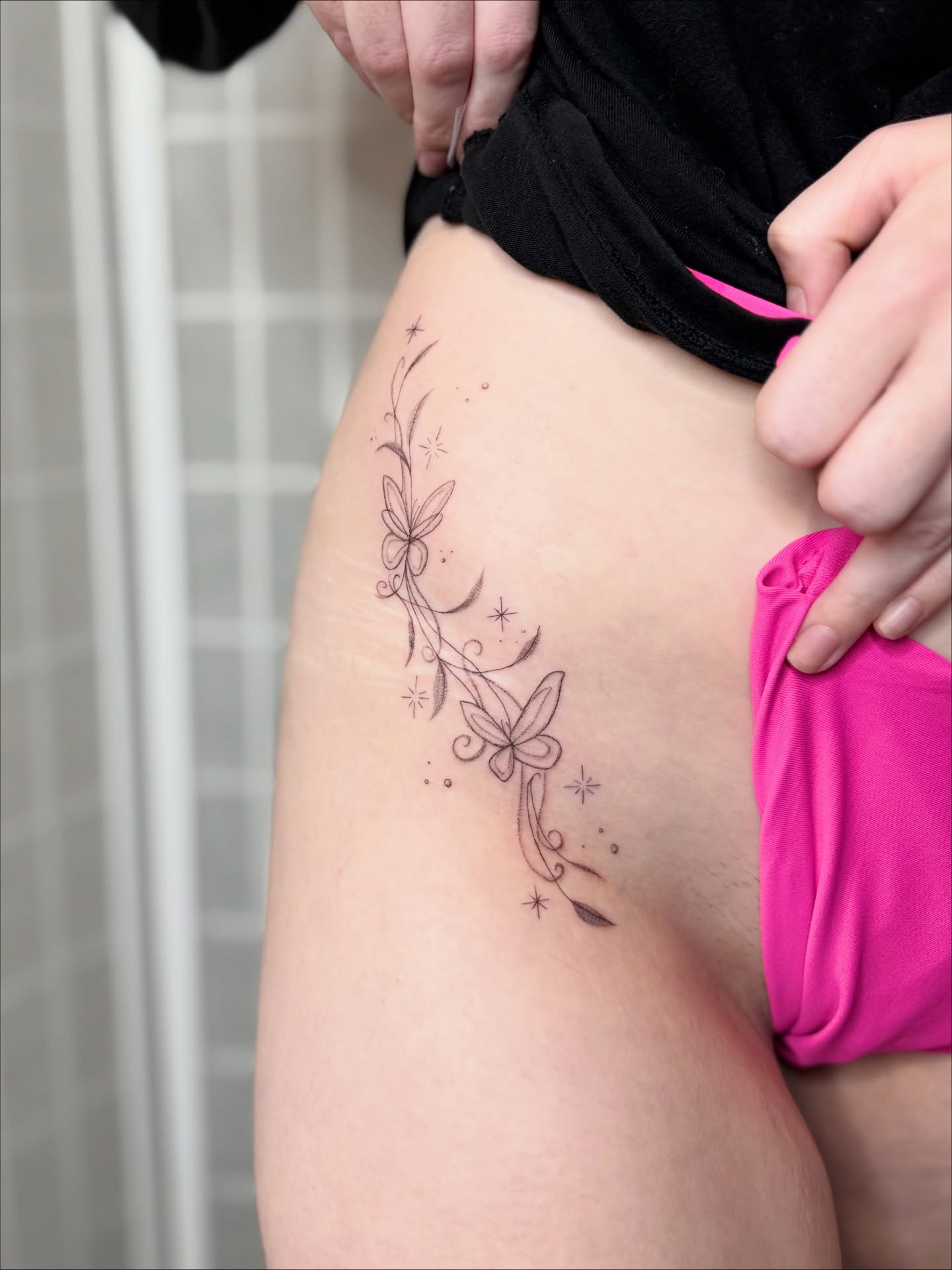 Floral vine fine line tattoo on the thigh by Dama