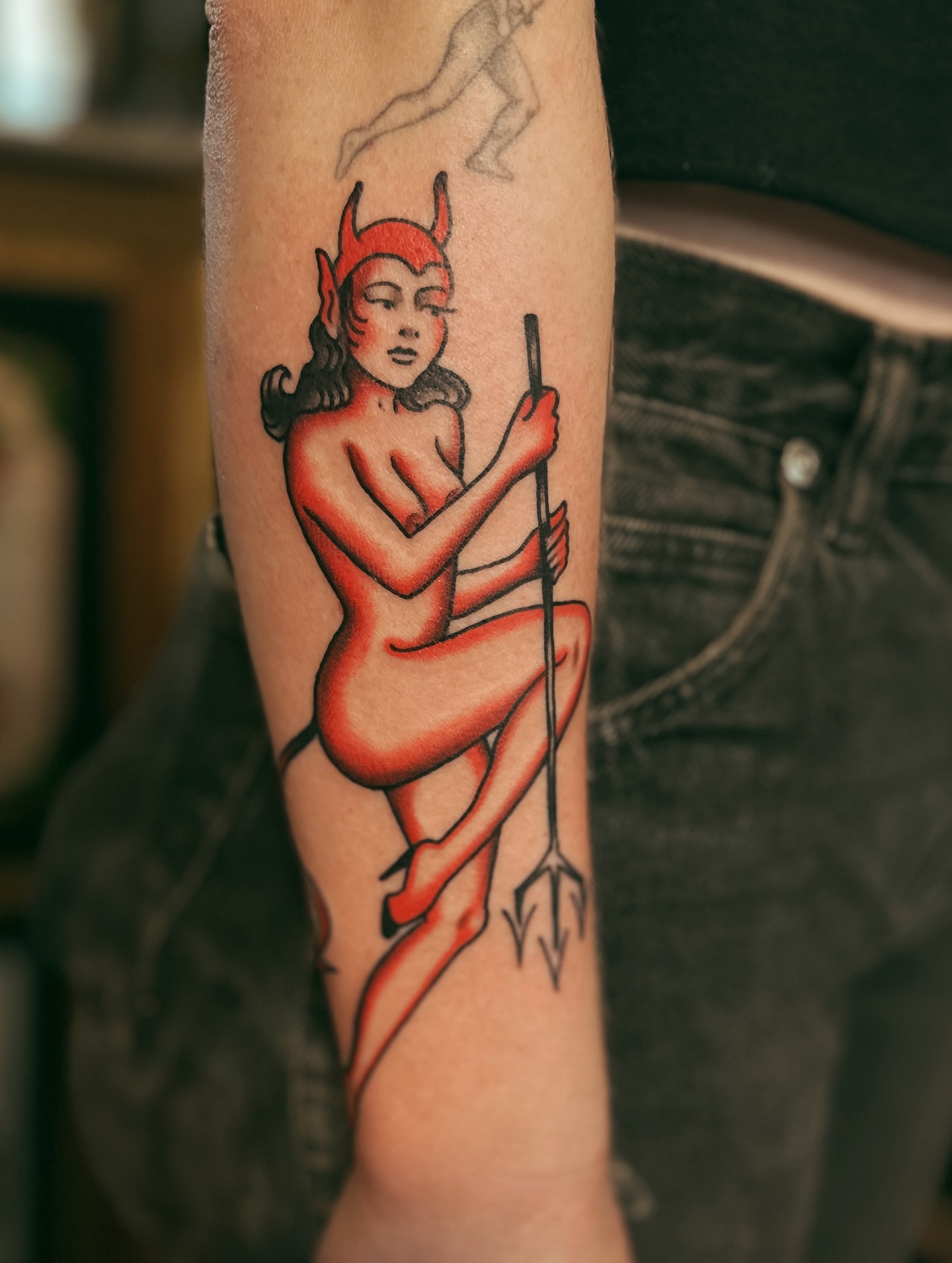 Red devil pin-up girl American traditional tattoo on the forearm by Holly Ellis, San Francisco, California