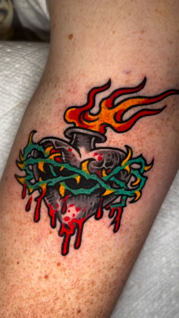 Flaming heart with crown of thorns American traditional tattoo on the forearm by Gabi Elia