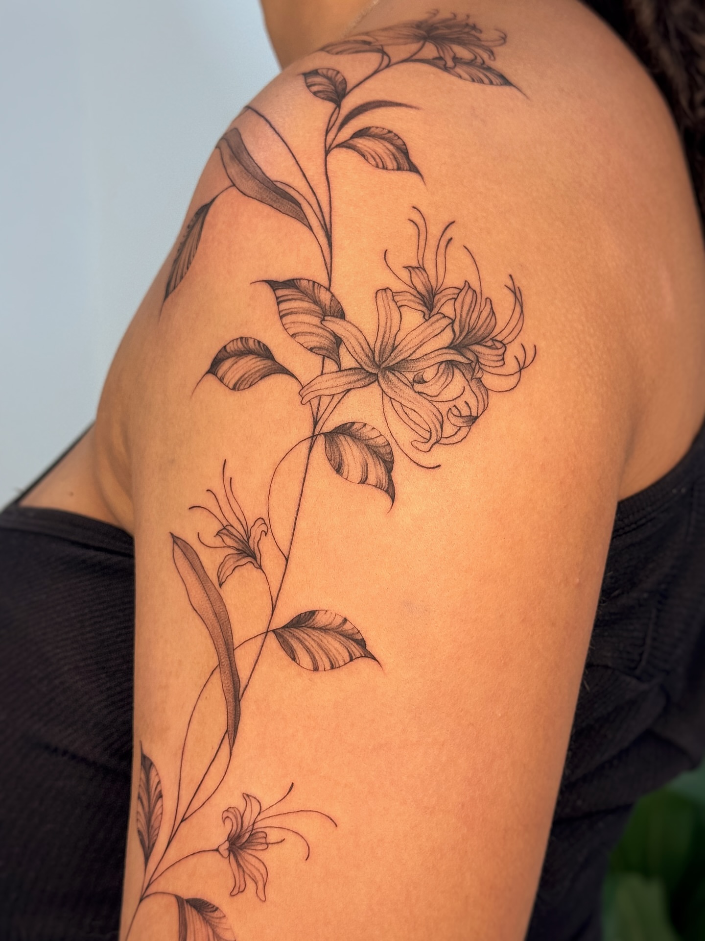 Lilies black and grey tattoo on the shoulder by Gianna Rodriguez