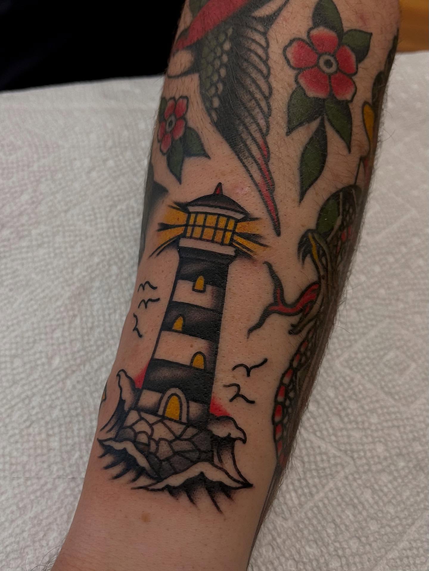 Lighthouse and flowers American traditional tattoo on the forearm by Christian Lasyone