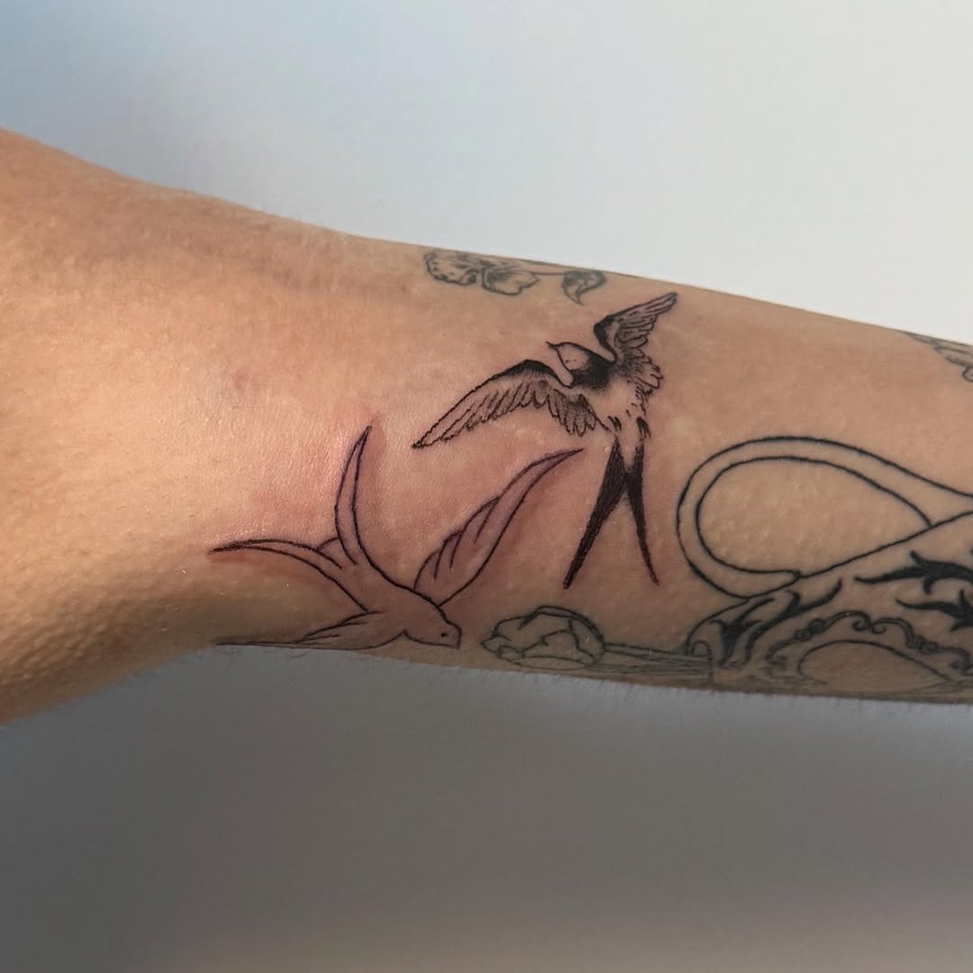 Two swallows fine line tattoo on the forearm by Kirsten