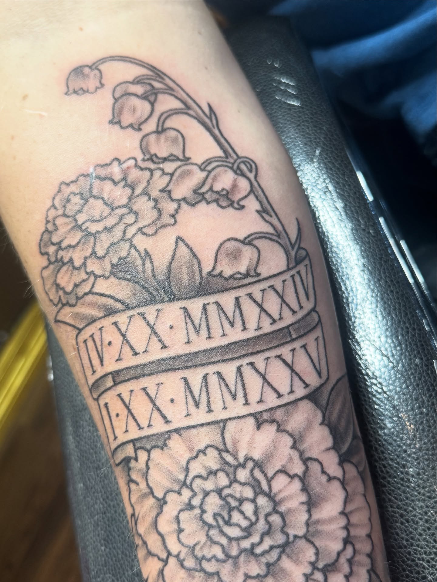 Flowers and Roman numerals black and grey tattoo on the forearm by Teagan Rachel, Millcreek, Utah