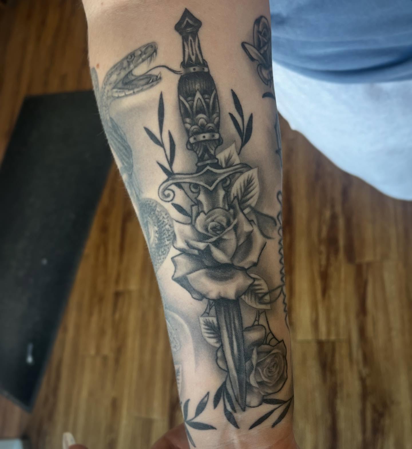 Sword and roses black and grey tattoo on the forearm by Taylor Santavicca