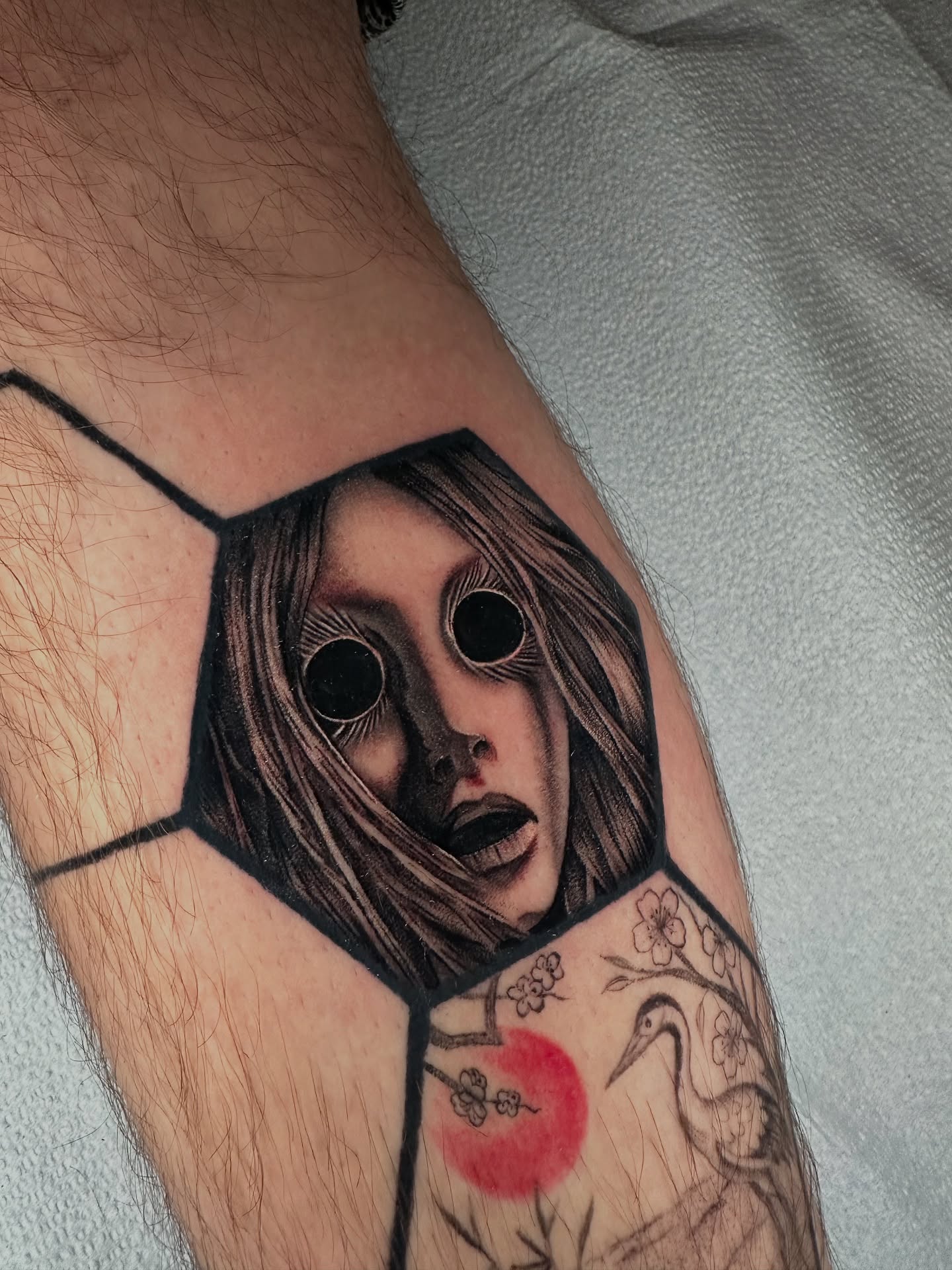 Horror mask geometric tattoo on the forearm by Sam Minneci