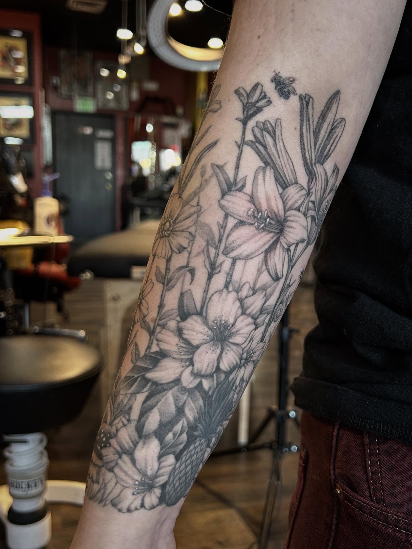 Flowers and bee black and grey tattoo on the forearm by Tako, Seattle, Washington