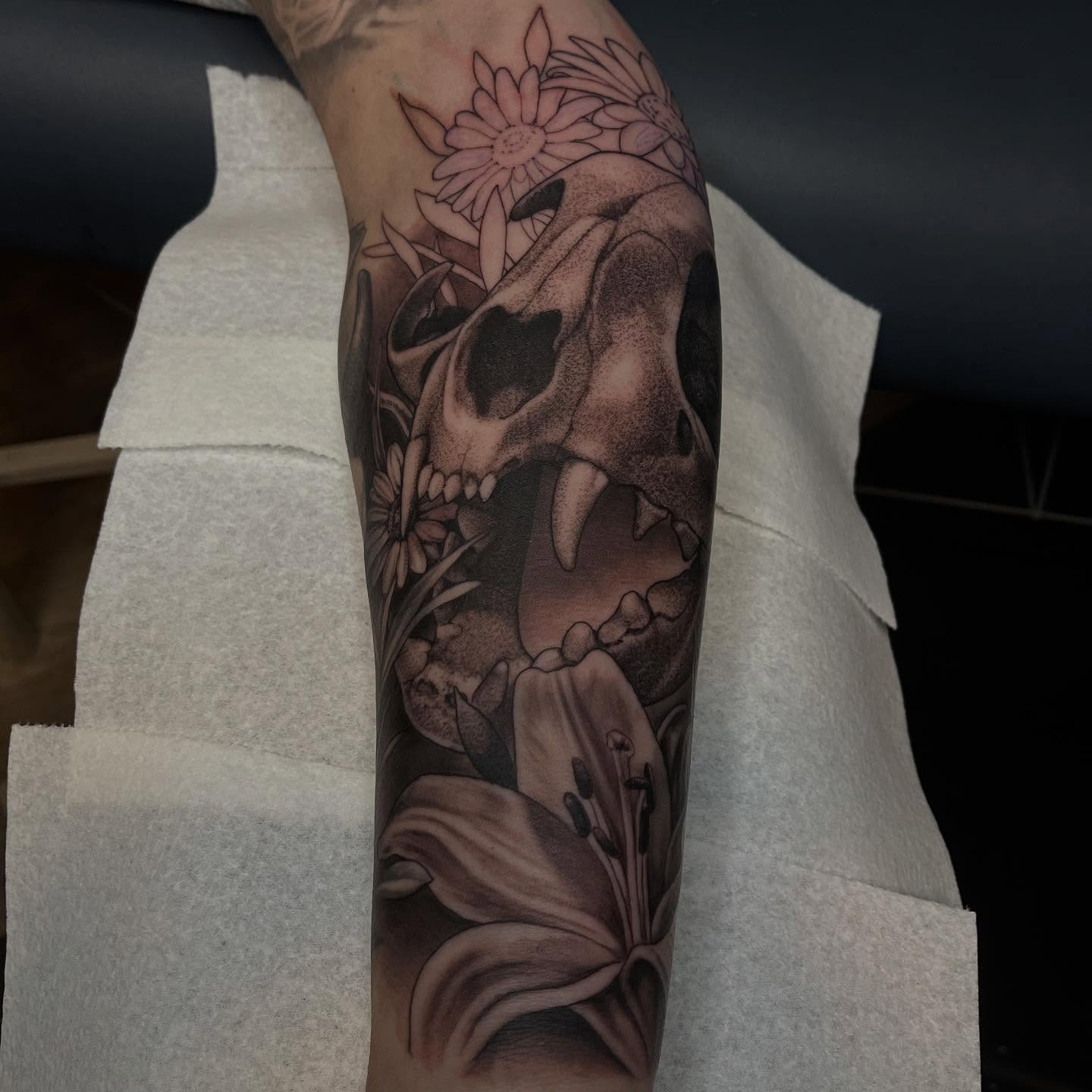 Skull and flowers realism tattoo on the forearm by Adam Habecker
