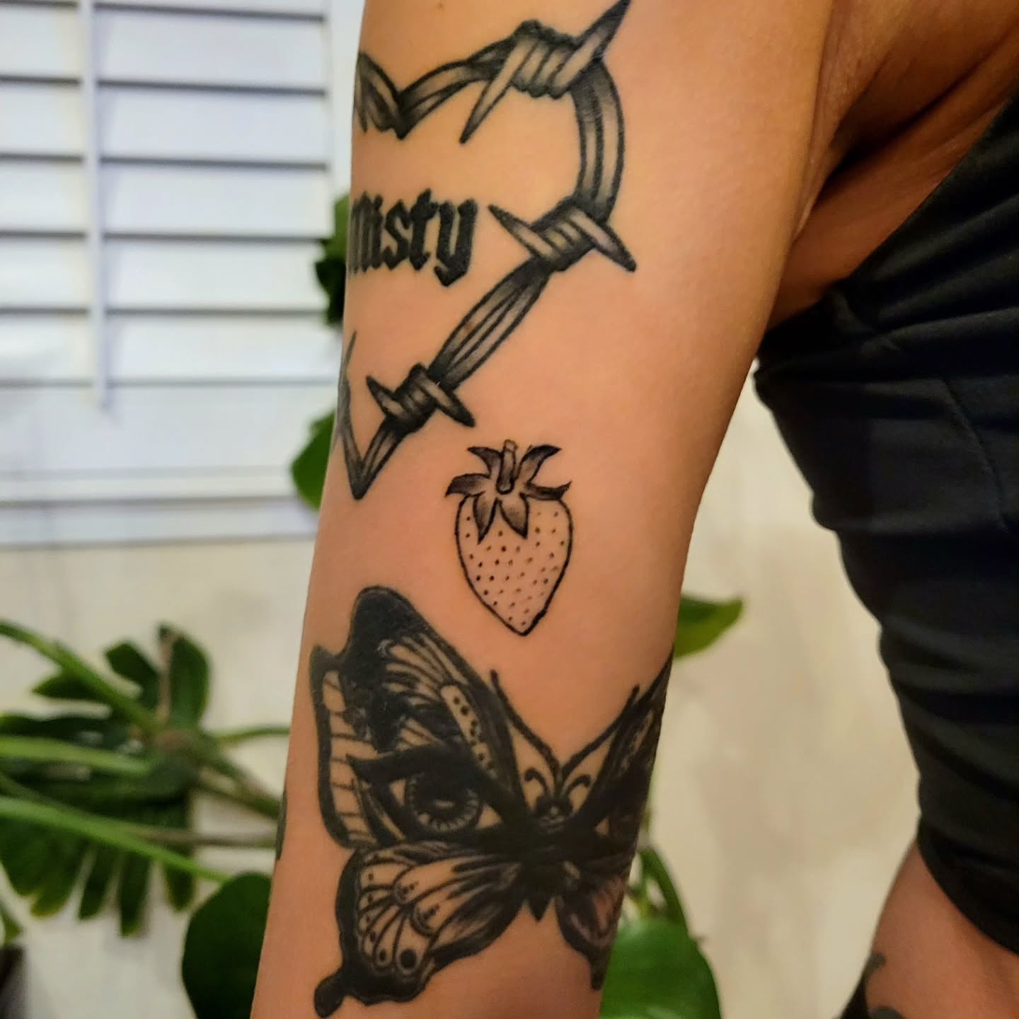 Barbed wire heart, strawberry, butterfly black and grey tattoo on the forearm by Kyle - Portland Oregon Tattoo Artist