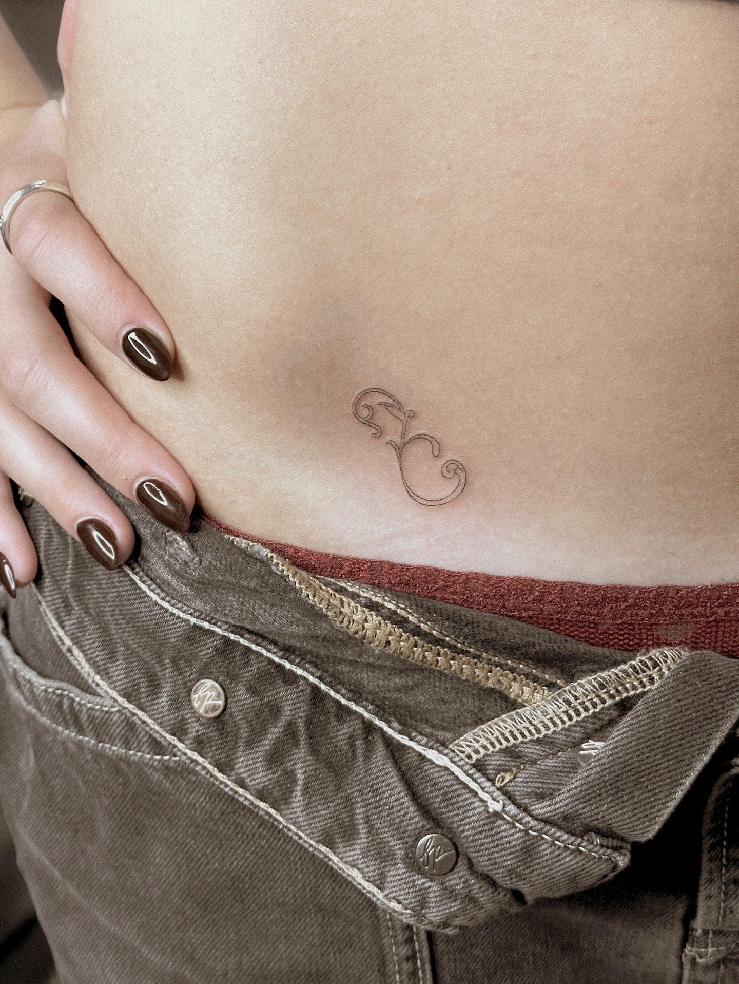 Curly symbol fine line tattoo on the torso by Yuli Noama