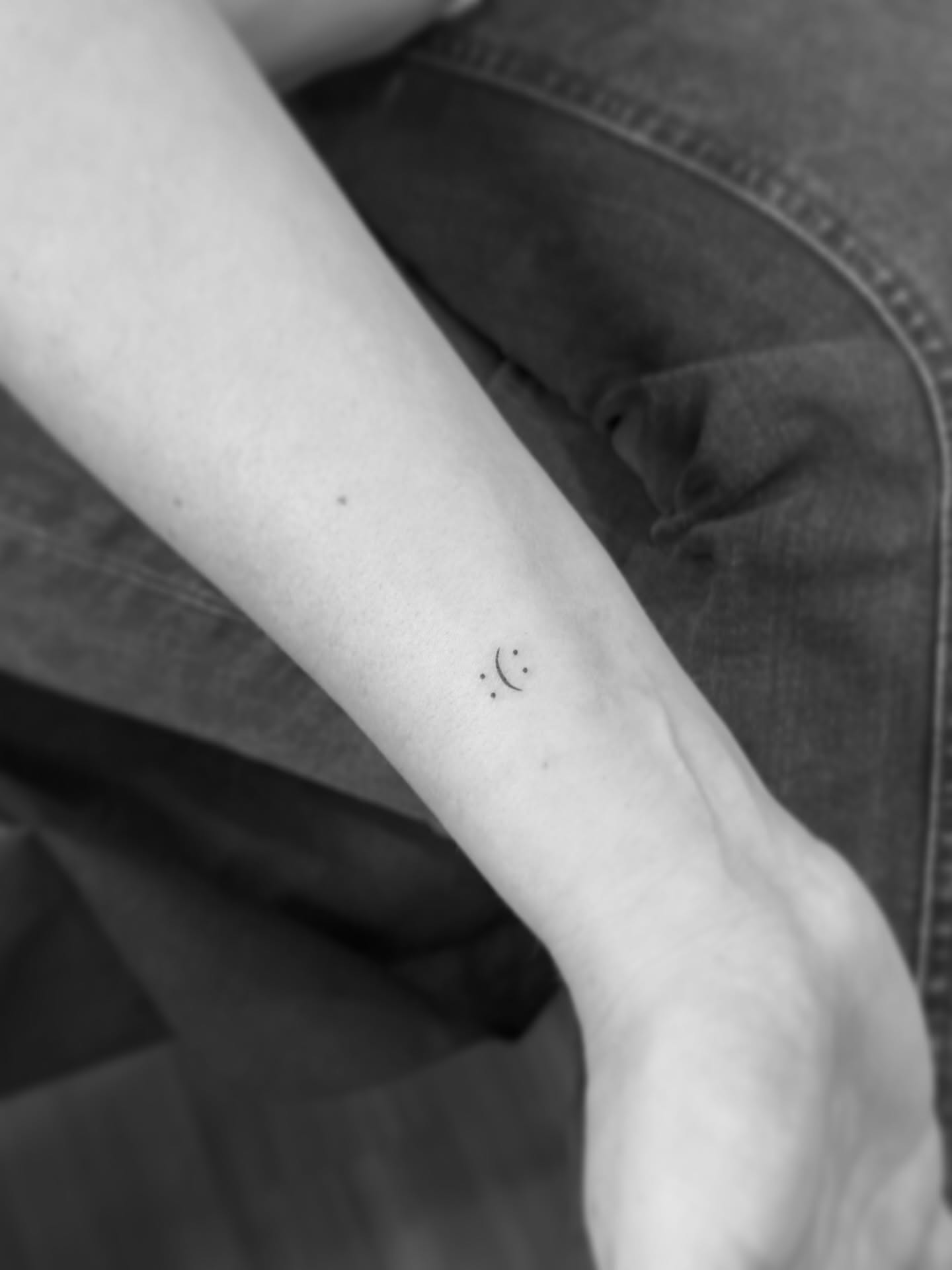 Smiley face dotwork tattoo on the forearm by Yuli Noama