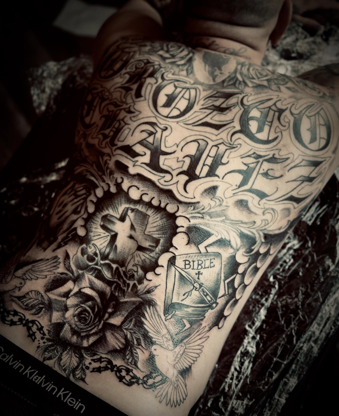 Cross and Bible black and grey tattoo on the back by Jessica Abbey