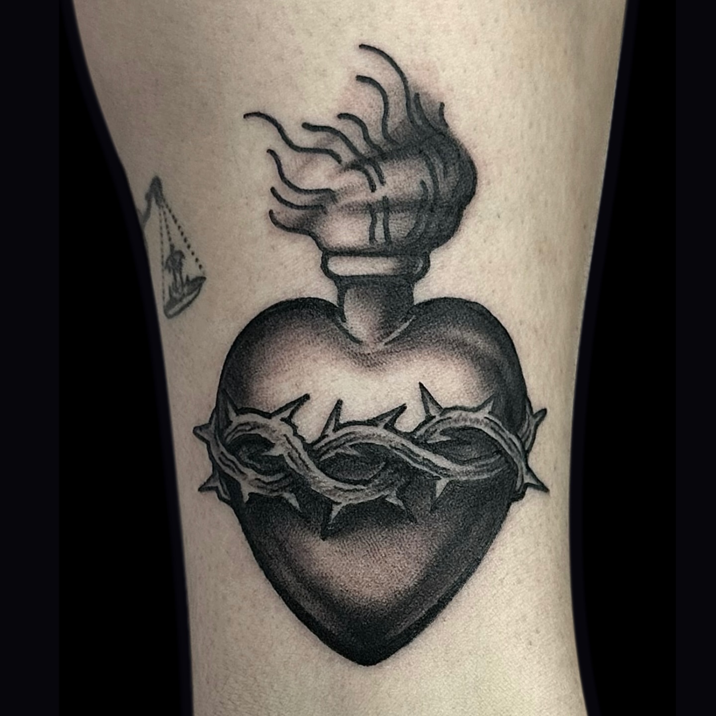 Heart with crown of thorns black and grey tattoo on the forearm by Madeline Brown