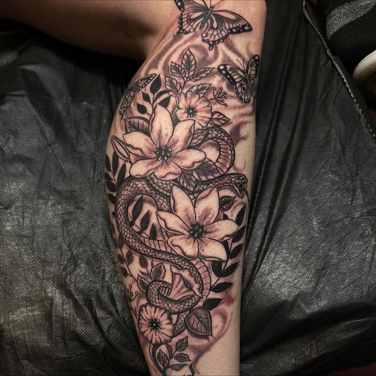 Snake and flowers black and grey tattoo on the forearm by Gary Chase