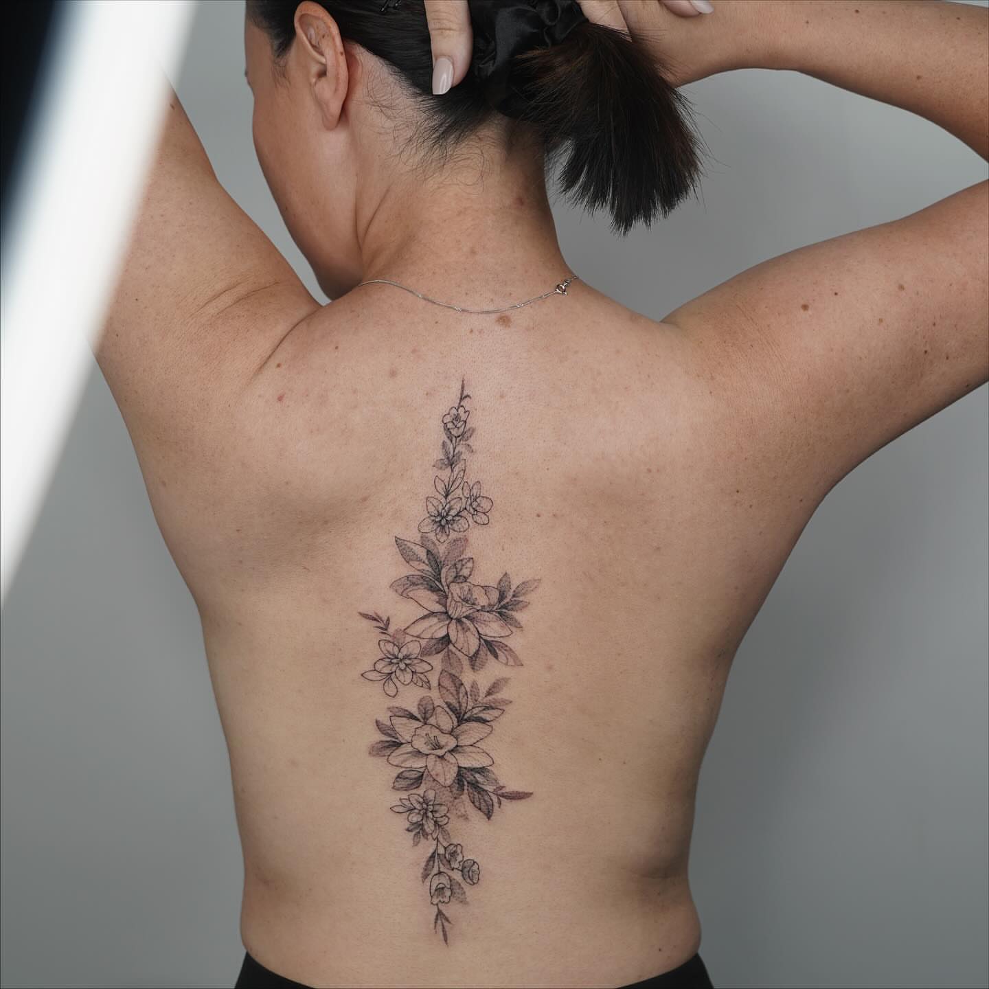 Floral arrangement black and grey tattoo on the back by Emma