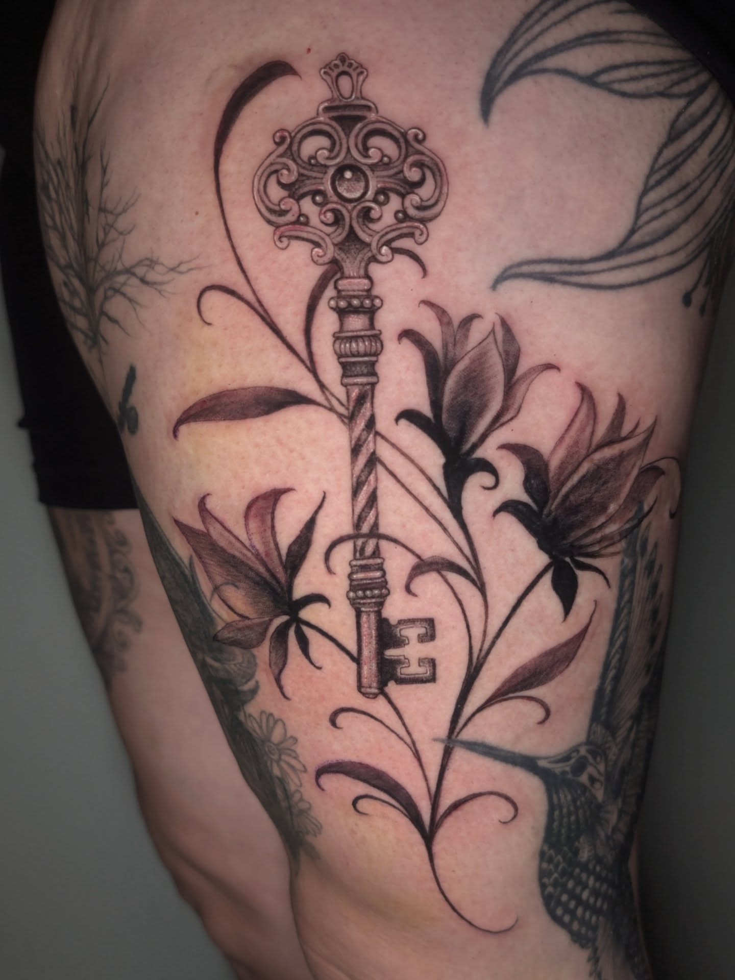Key and floral ornamental tattoo on the thigh by 💎 Neon